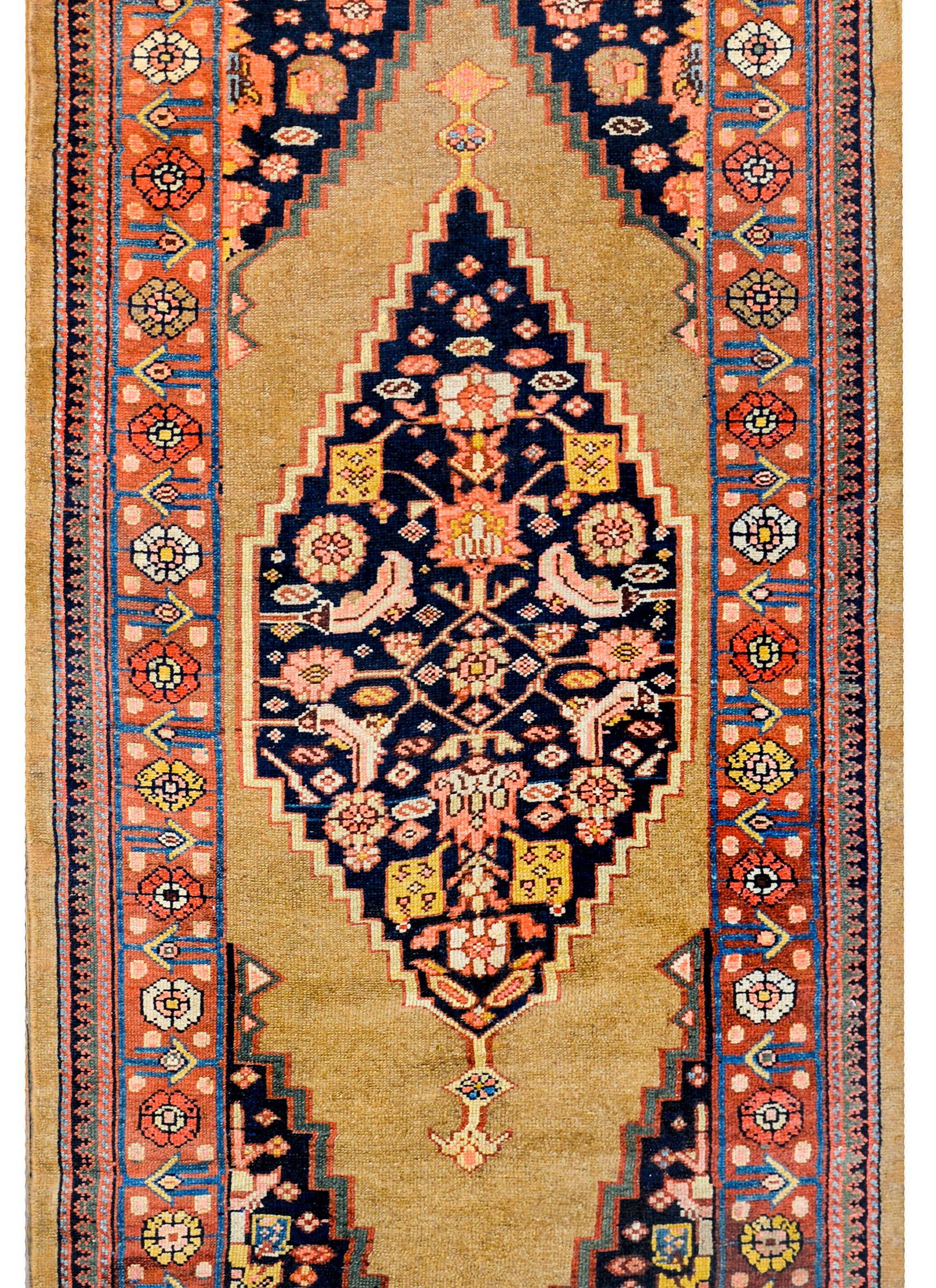 An early 20th century Persian Serab runner with an asymmetrical pattern with a floral patterned diamond on one end and the reverse pattern on the other all woven in pink, gold, and indigo surrounded by natural camel hair. The border is wonderful