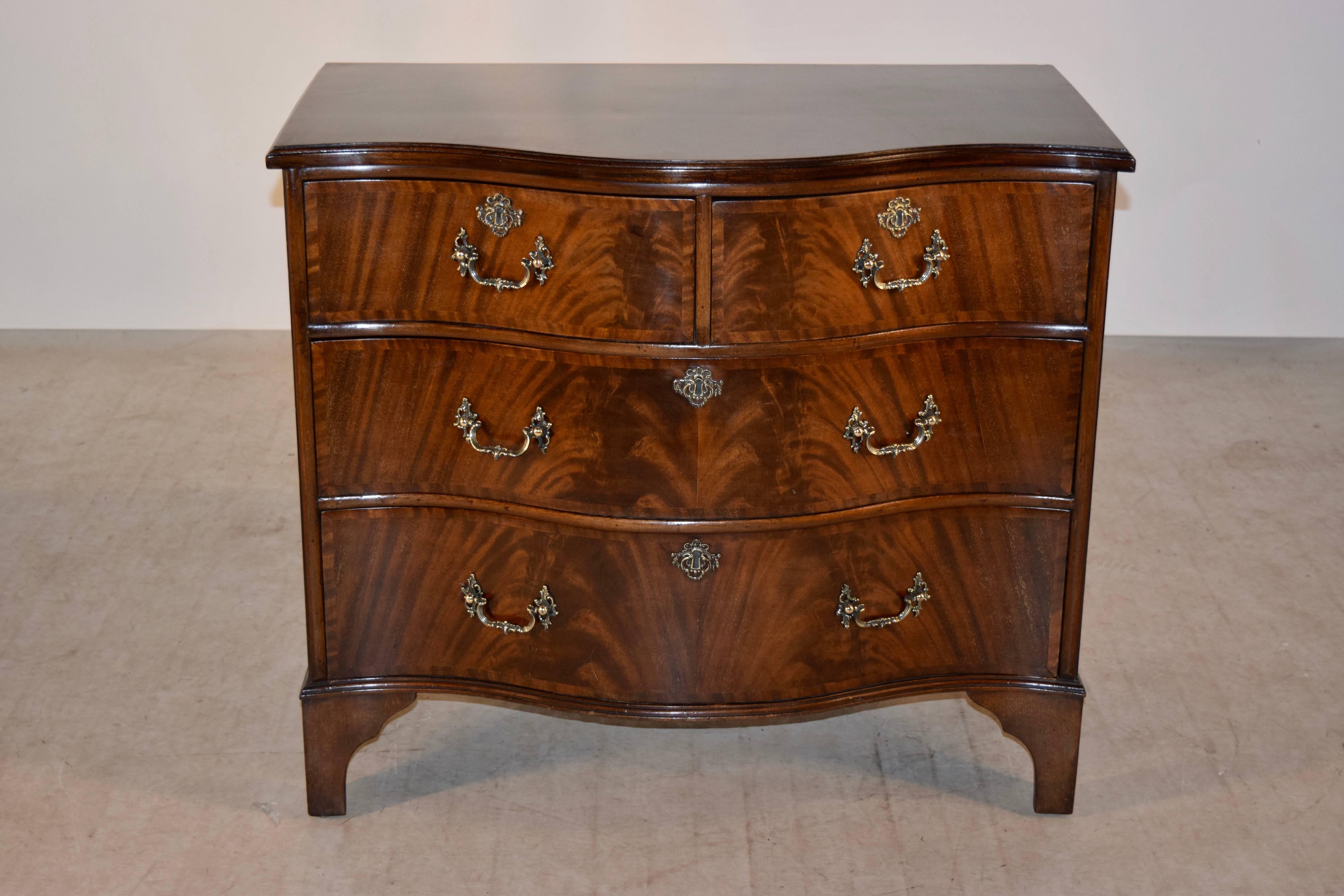 Early 20th century English serpentine chest of drawers made from mahogany. The top is wonderfully grained and follows down to simple sides and a serpentine shaped front containing two drawers over two drawers over bracket feet.