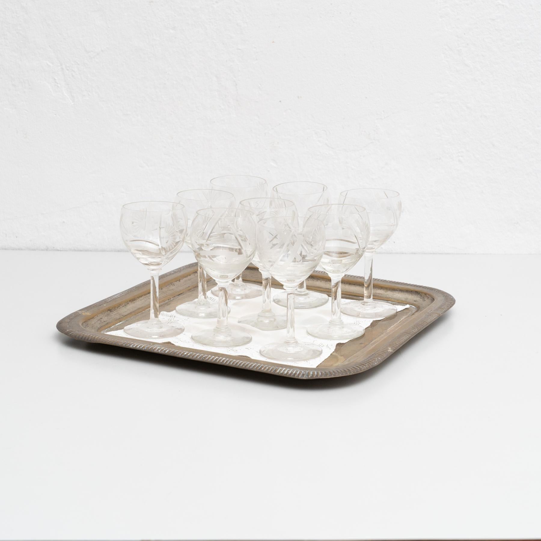 Antiguo juego francés de 9 copas de vino de cristal sobre bandeja de latón.    Fabricado por un fabricante desconocido en Francia, hacia 1950.    En su estado original, con pequeños desgastes propios de la edad y el uso, conserva una hermosa pátina.