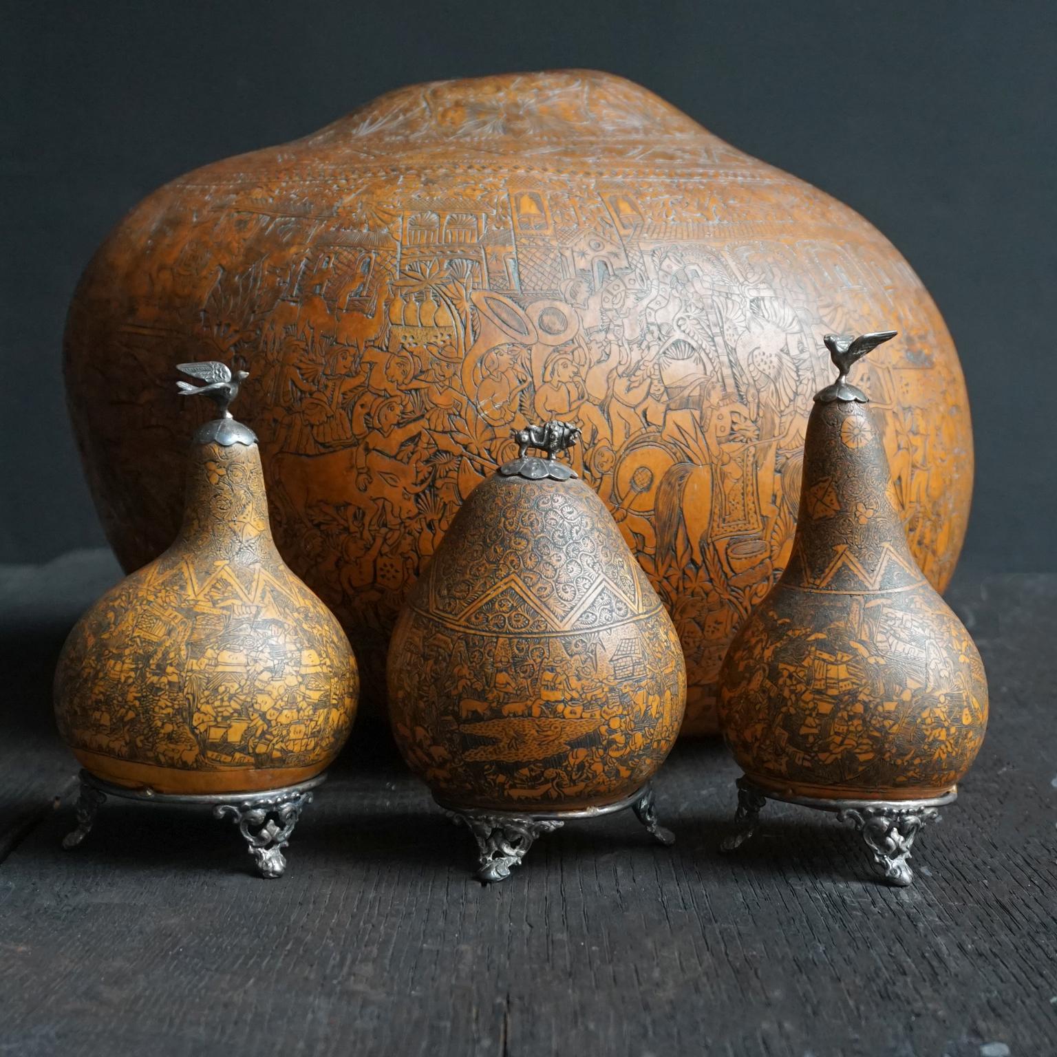 Set of four antique carved gourds from Peru, three little ones with silver settings and decorations and a large carved gourd.

A Gourd is a crop plant in the family Cucurbitaceae, like pumpkins, cucumbers, squash, luffa, and melons.
'Gourd' refers