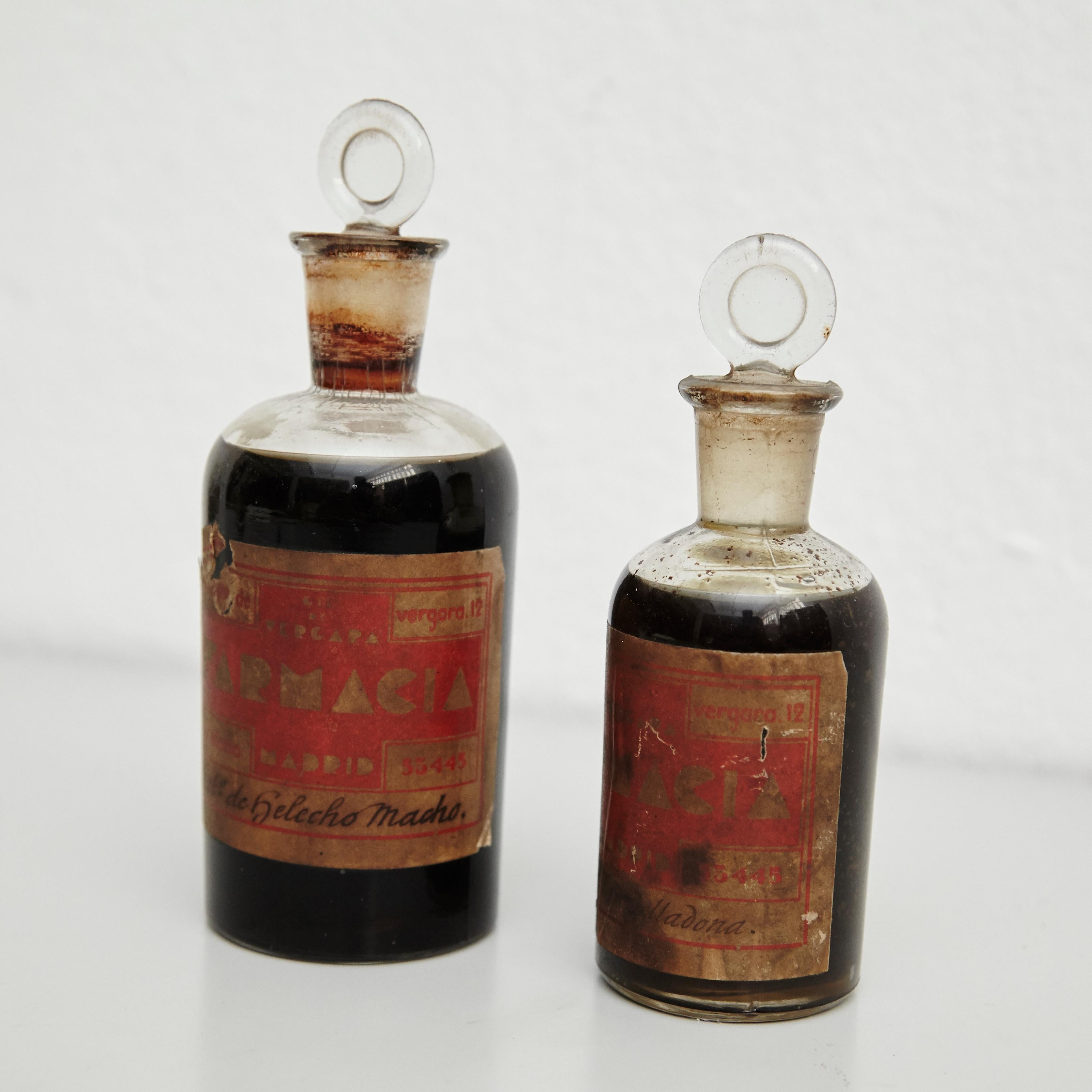 Early 20th century set of vintage rustic glass apothecary bottles.
By unknown manufacturer, Spain.

In original condition, with minor wear consistent with age and use, preserving a beautiful patina.

Materials:
Glass

Dimensions:
Large: ø