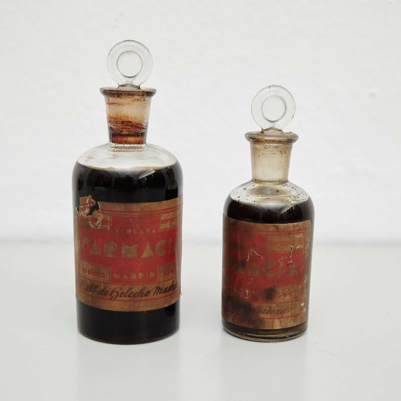Early 20th century set of vintage rustic glass apothecary bottles.
By unknown manufacturer, Spain.

In original condition, with minor wear consistent with age and use, preserving a beautiful patina.

Materials:
Glass

Dimensions:
Large: ø