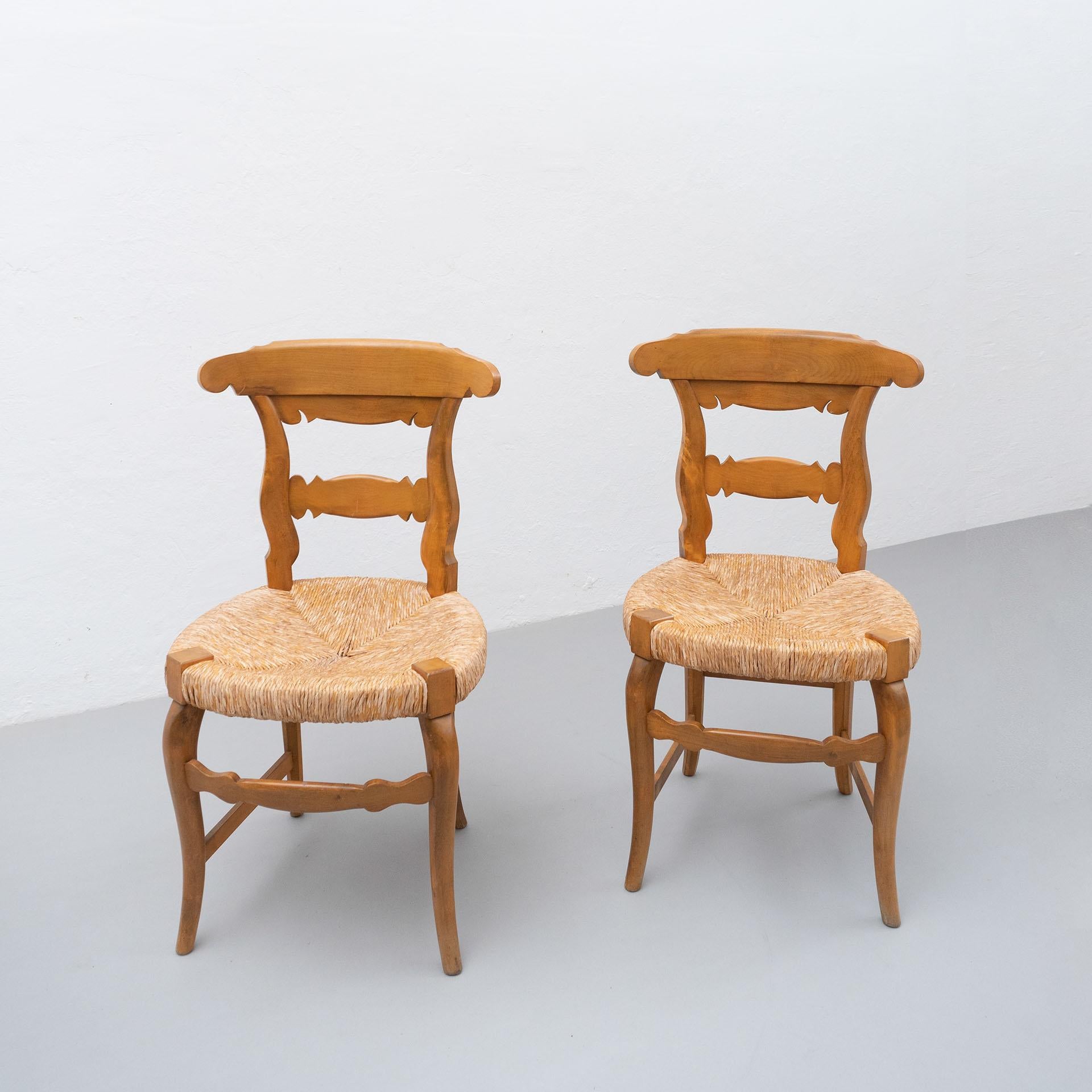 Early 20th century set of two provenzal chairs. Wooden chairs with a traditional rattan seat, curved lines and characteristic details of French Provincial style.

In good original condition, with minor wear consistent with age and use, preserving