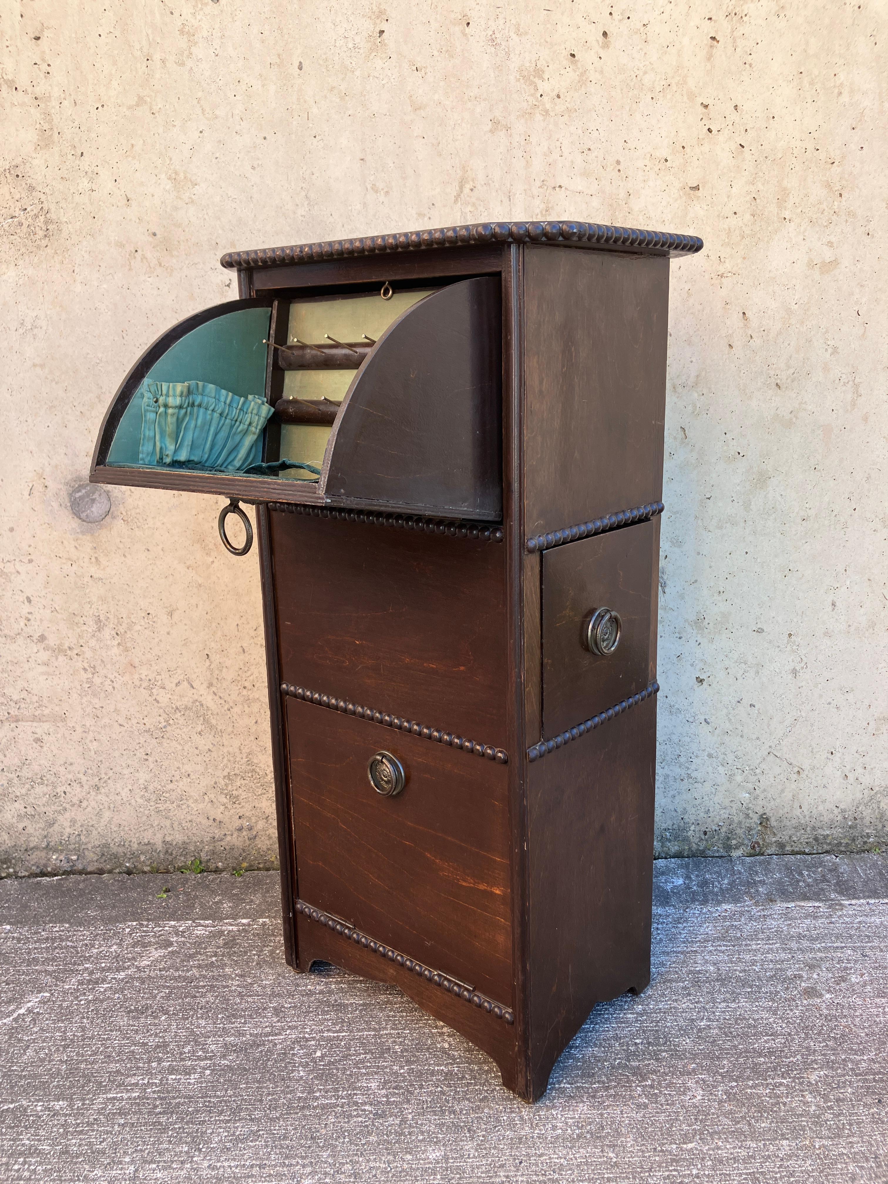 Charmante armoire à travaux d'aiguille en bois du début du 20e siècle, avec de petits compartiments pour le coton et les aiguilles. L'intérieur est doublé de soie vert clair. Fabriqué en Angleterre.

Bon état pour l'âge, avec quelques usures à la