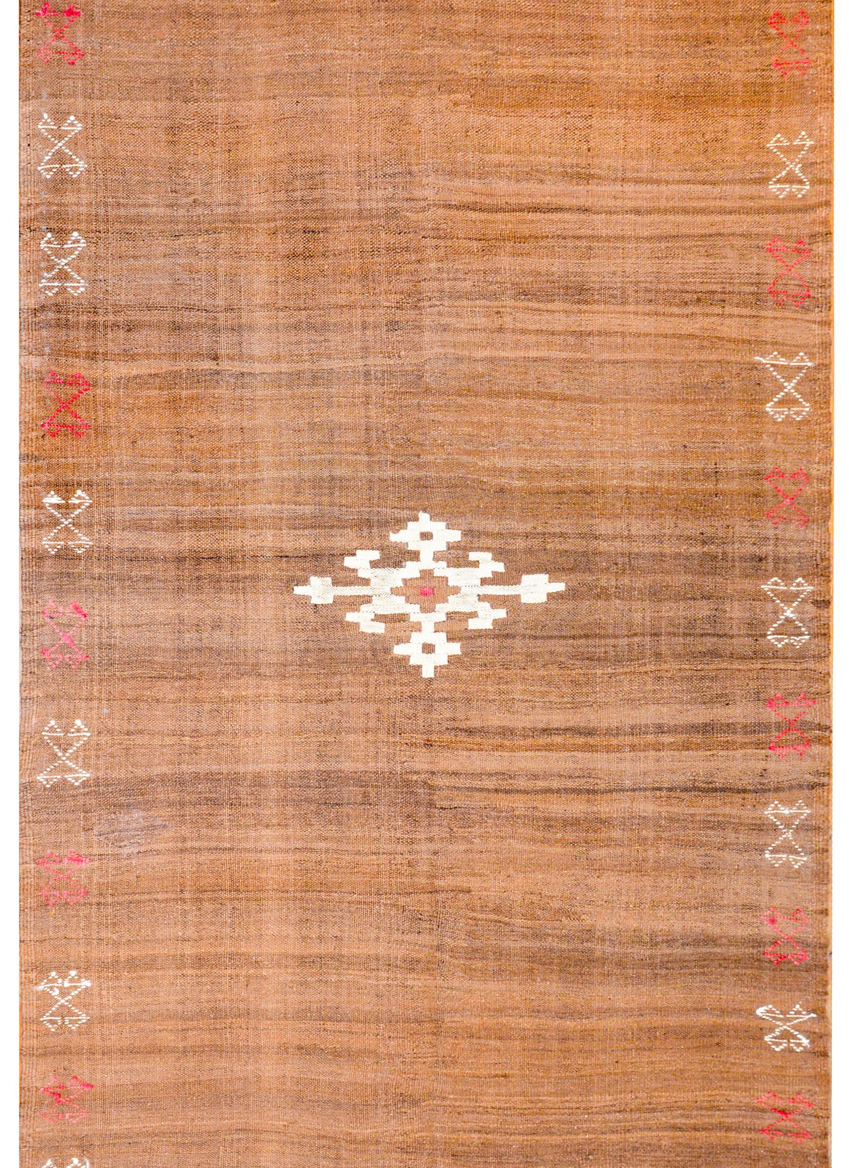 A wonderful early 20th century Persian Shahsavan Kilim rug with a simle, but beautiful, field woven in natural undyed wool with varying shades of brown. A geometric-styled diamond medallion lives in the centre, and alternating crimson and white