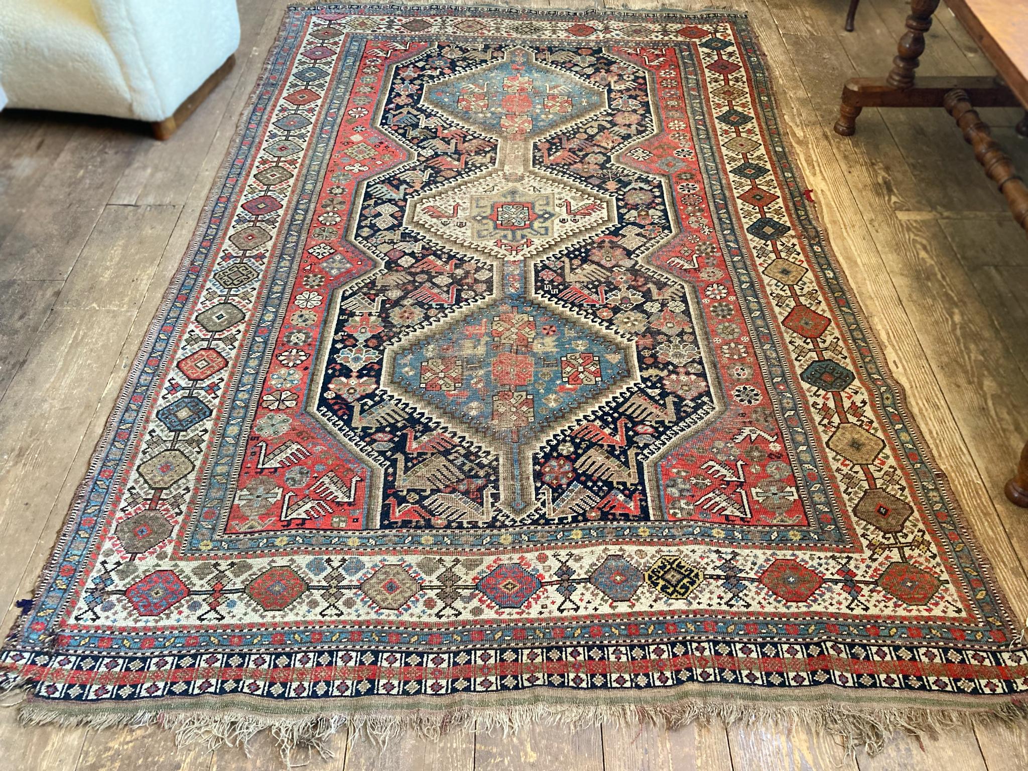 Shiraz rug hand-woven in the first quarter of the 20th Century. The design features three central medallions surrounded by flowers and peacocks and a series of borders with geometric patterns, all in a rich palette of blue, yellow, red, and ivory