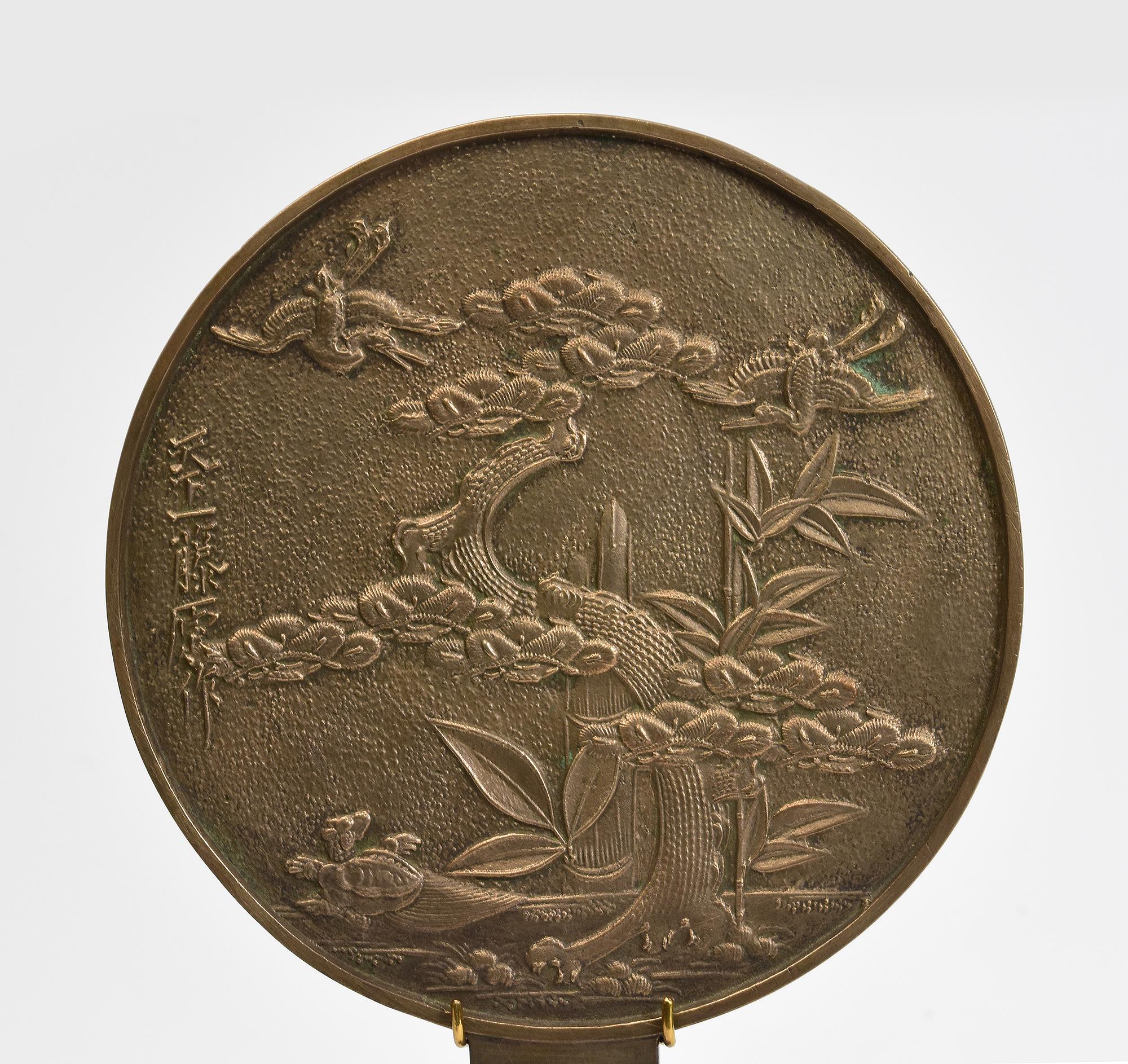 Japanese bronze mirror with stand.

Age: Japan, Showa Period, Early 20th Century
Size: Diameter 14.8 C.M. / Height 24.7 C.M.
Size including stand: Height 34 C.M.
Condition: Nice condition overall.