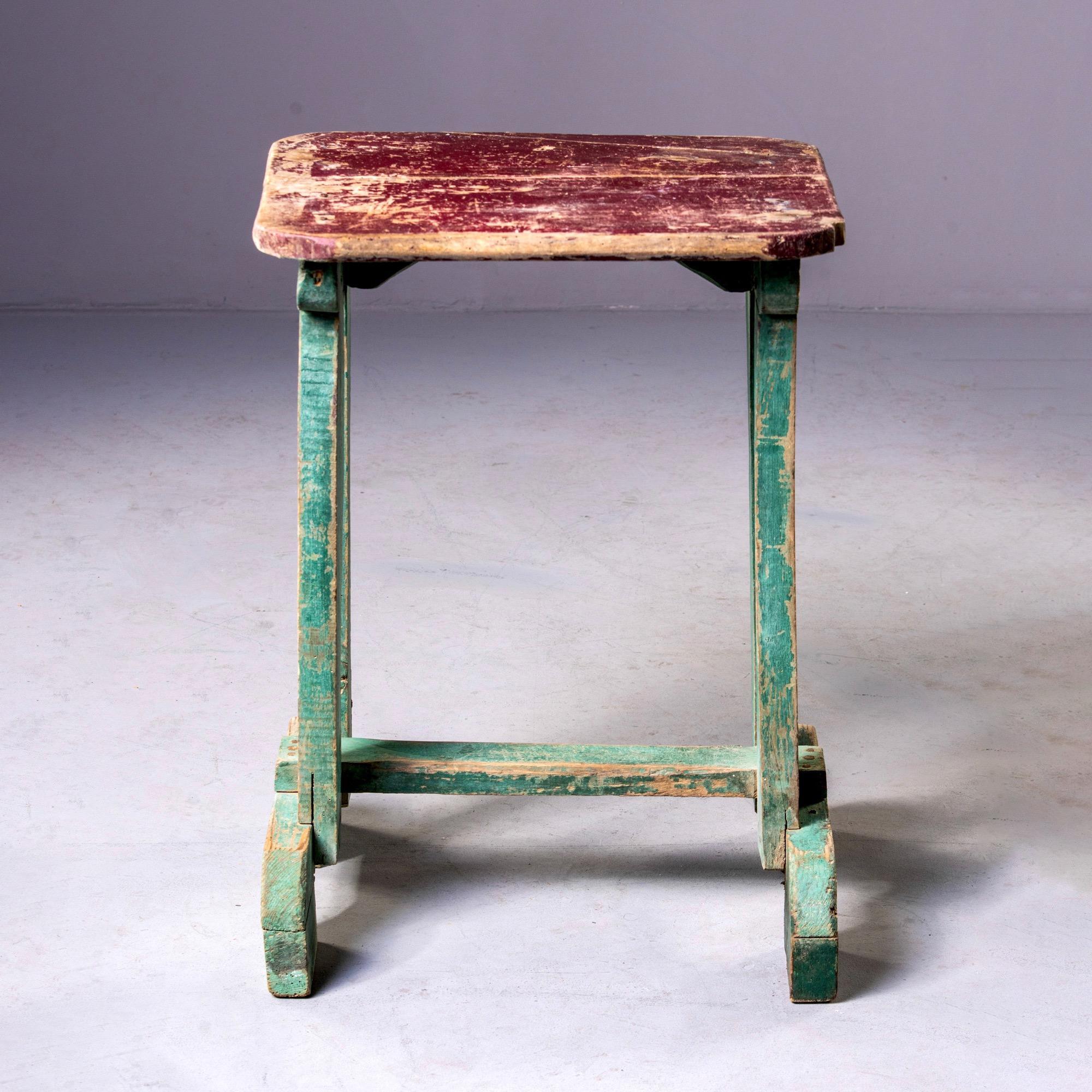 Painted wood side table found in England, circa 1900s. Original red paint on table top and green paint on base. Unknown maker.
