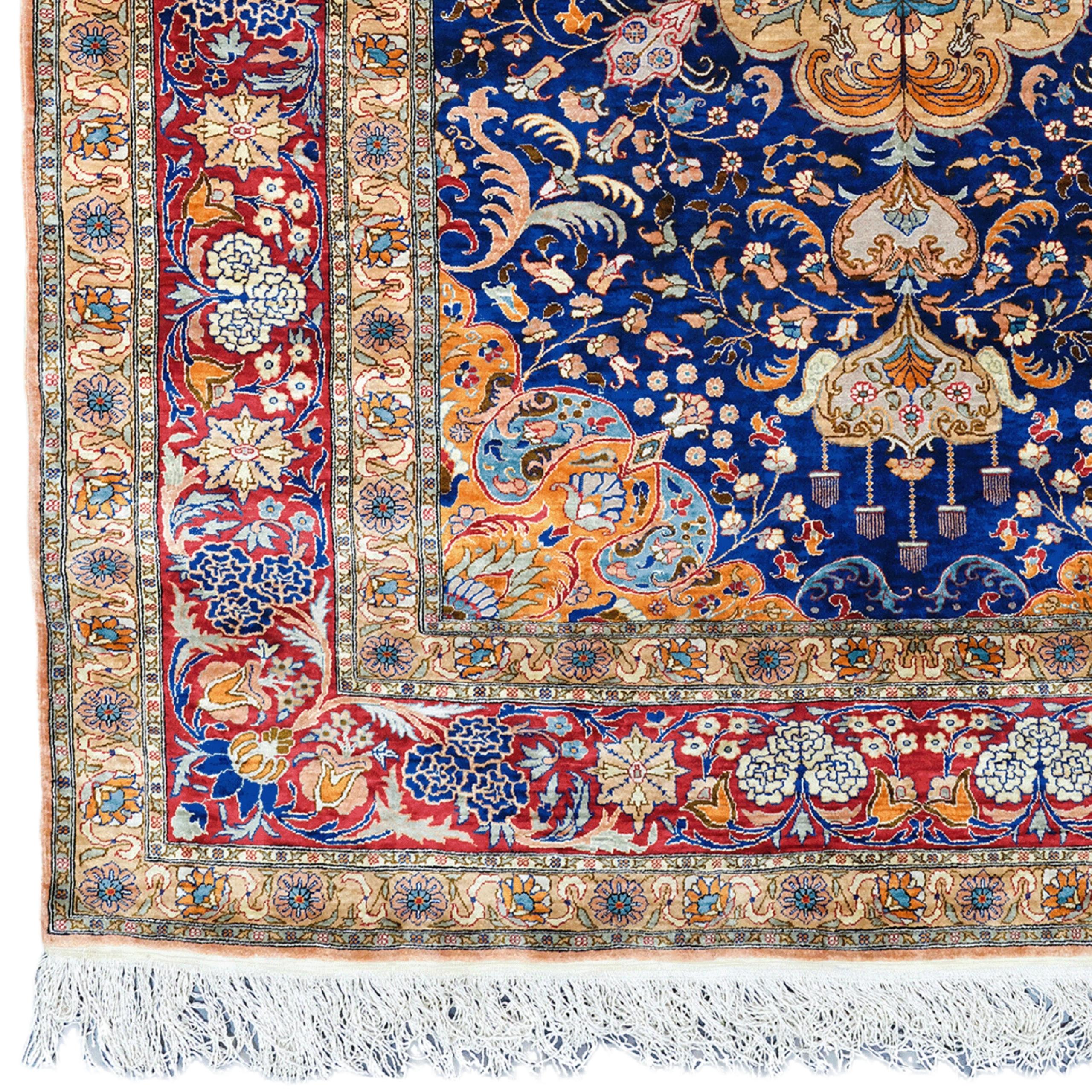 This gorgeous 20th century vintage silk Hereke rug comes from the famous weaving town of Hereke in Turkey. This hand-woven masterpiece has a rich history and unmatched quality. The deep navy blue central area is adorned with a detailed central