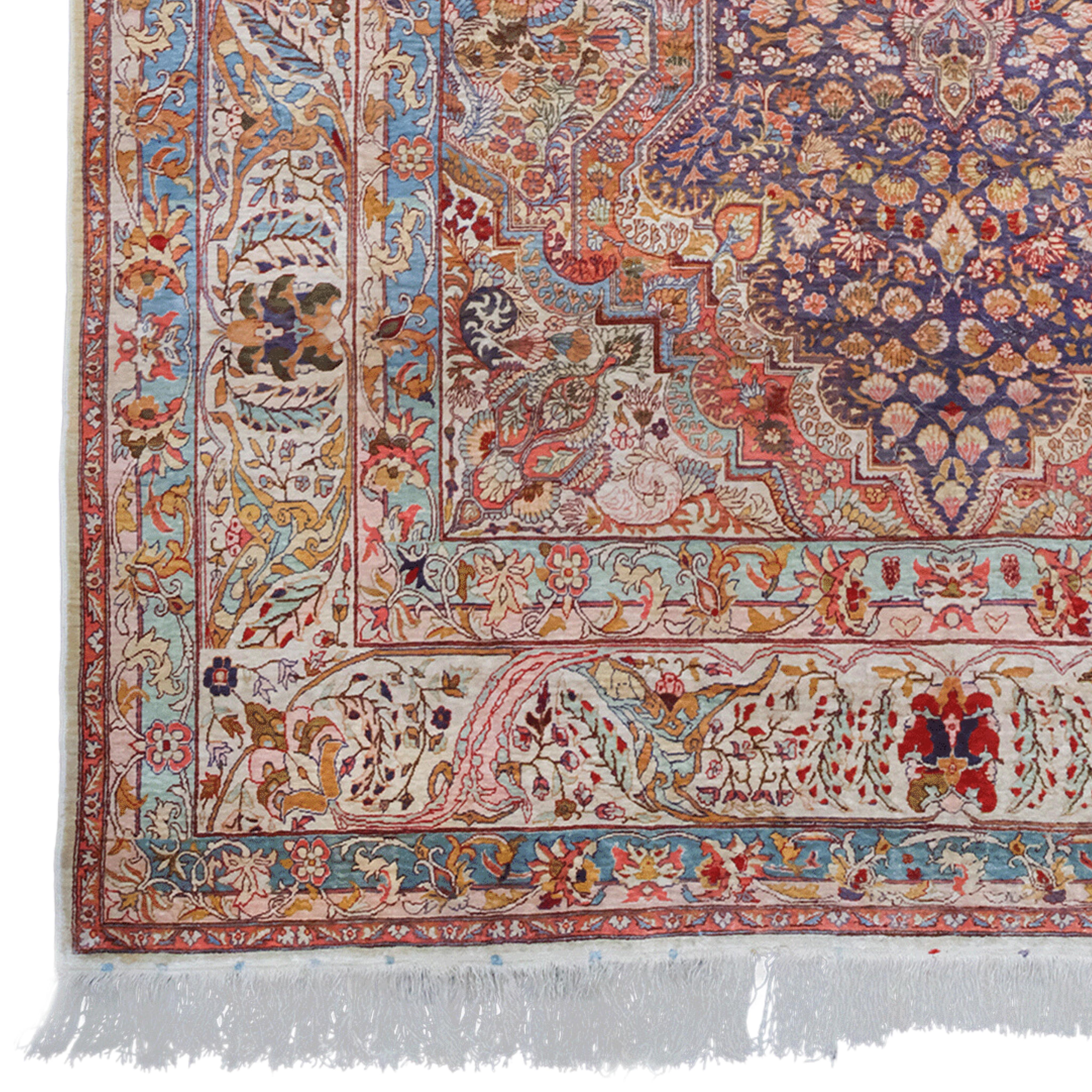 This gorgeous 20th century vintage silk Hereke rug comes from the famous weaving town of Hereke in Turkey. This hand-woven masterpiece has a rich history and unmatched quality. The deep navy blue central area is adorned with a detailed central