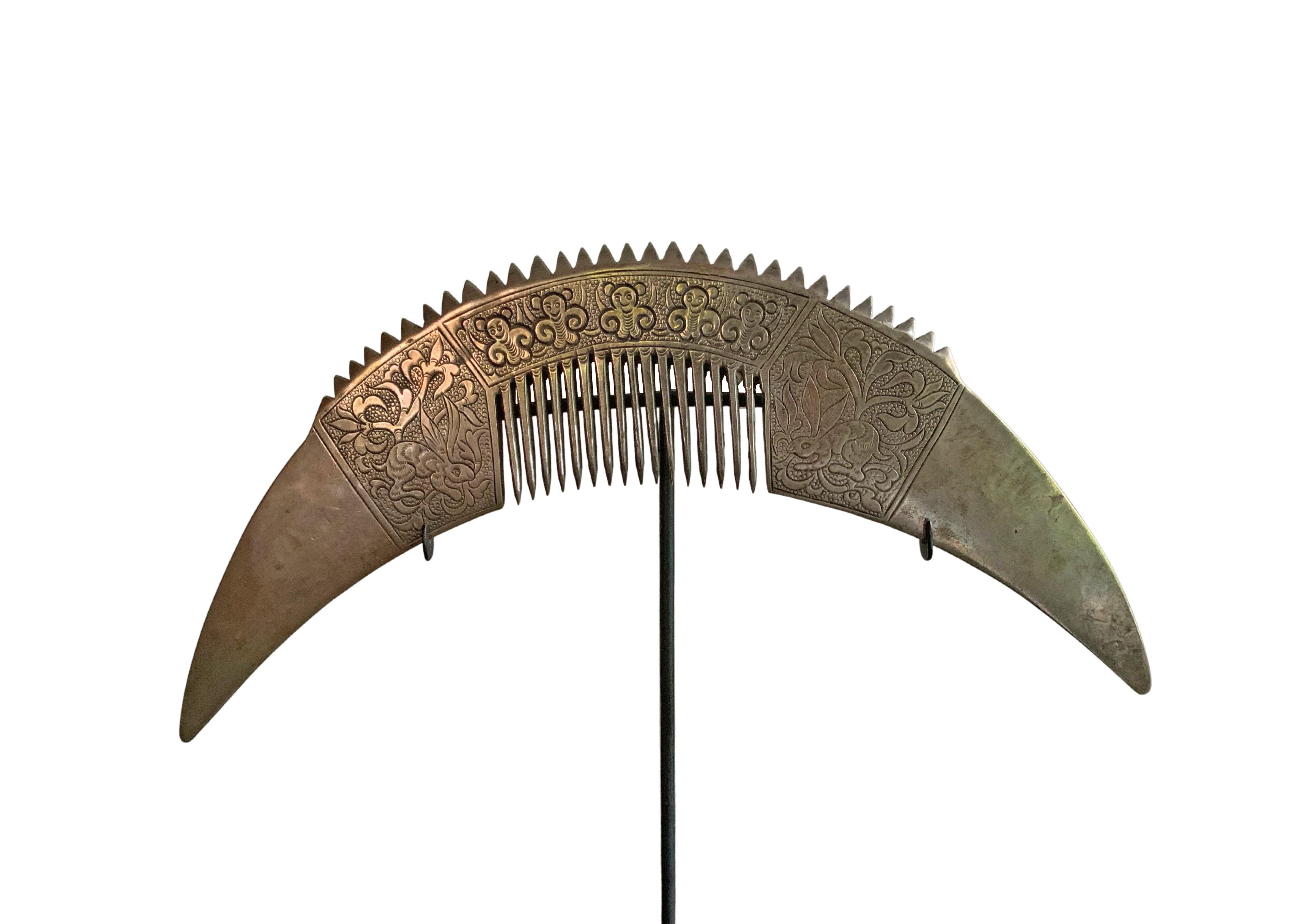 An early 20th century Chinese silver comb with engravings, mounted on a stand. 

Dimensions; Height with stand 21cm / Height 10cm x Width 23cm D 0.04cm.