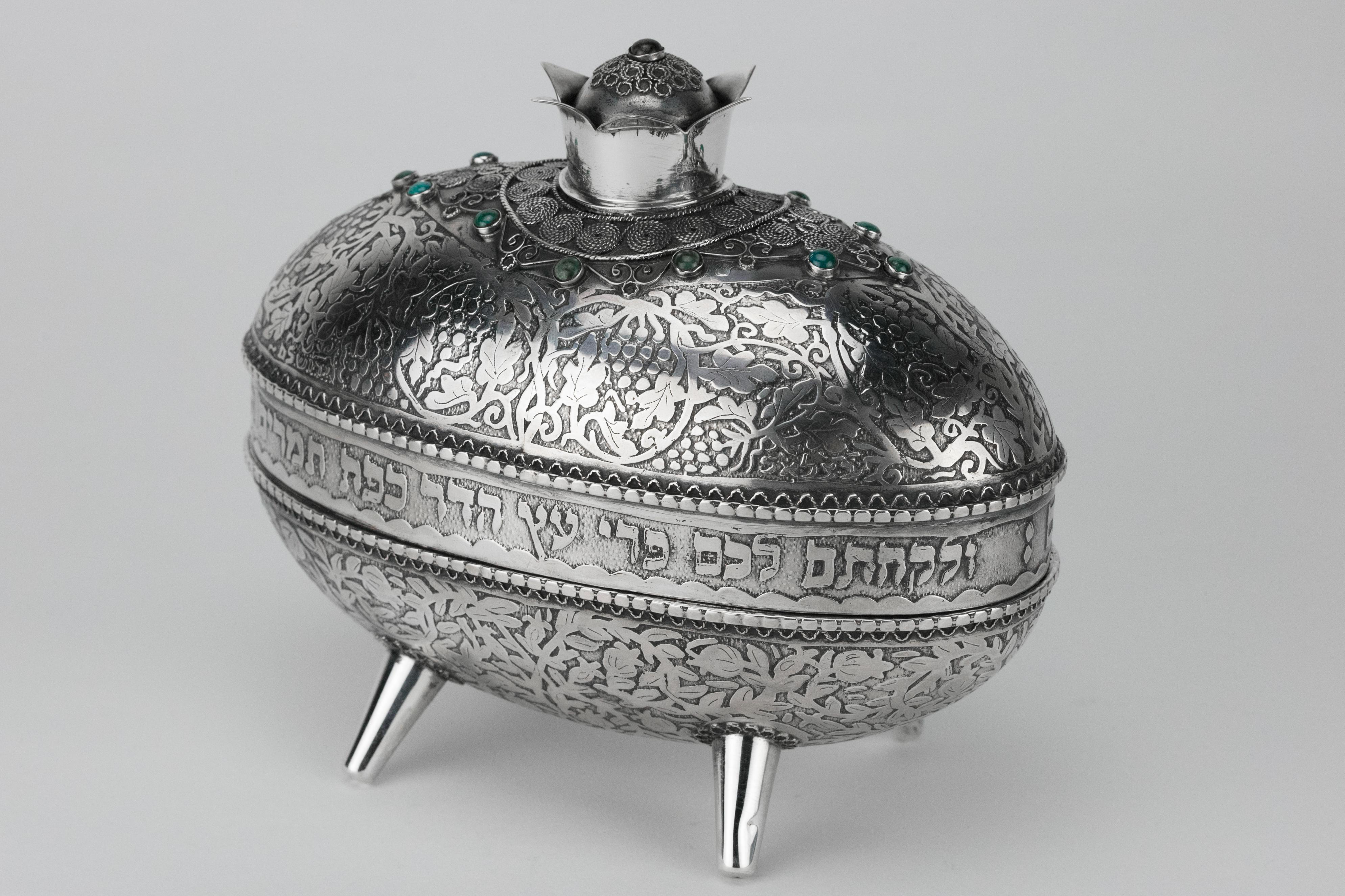 Silver and silver filigree etrog container, by Yehia Yemini, Bezalel School, Jerusalem, circa 1920.
Acid-etched decoration with grapes and vines on the lid, and with pomegranates and leaves on the base, decorated with silver filigree on the lid,