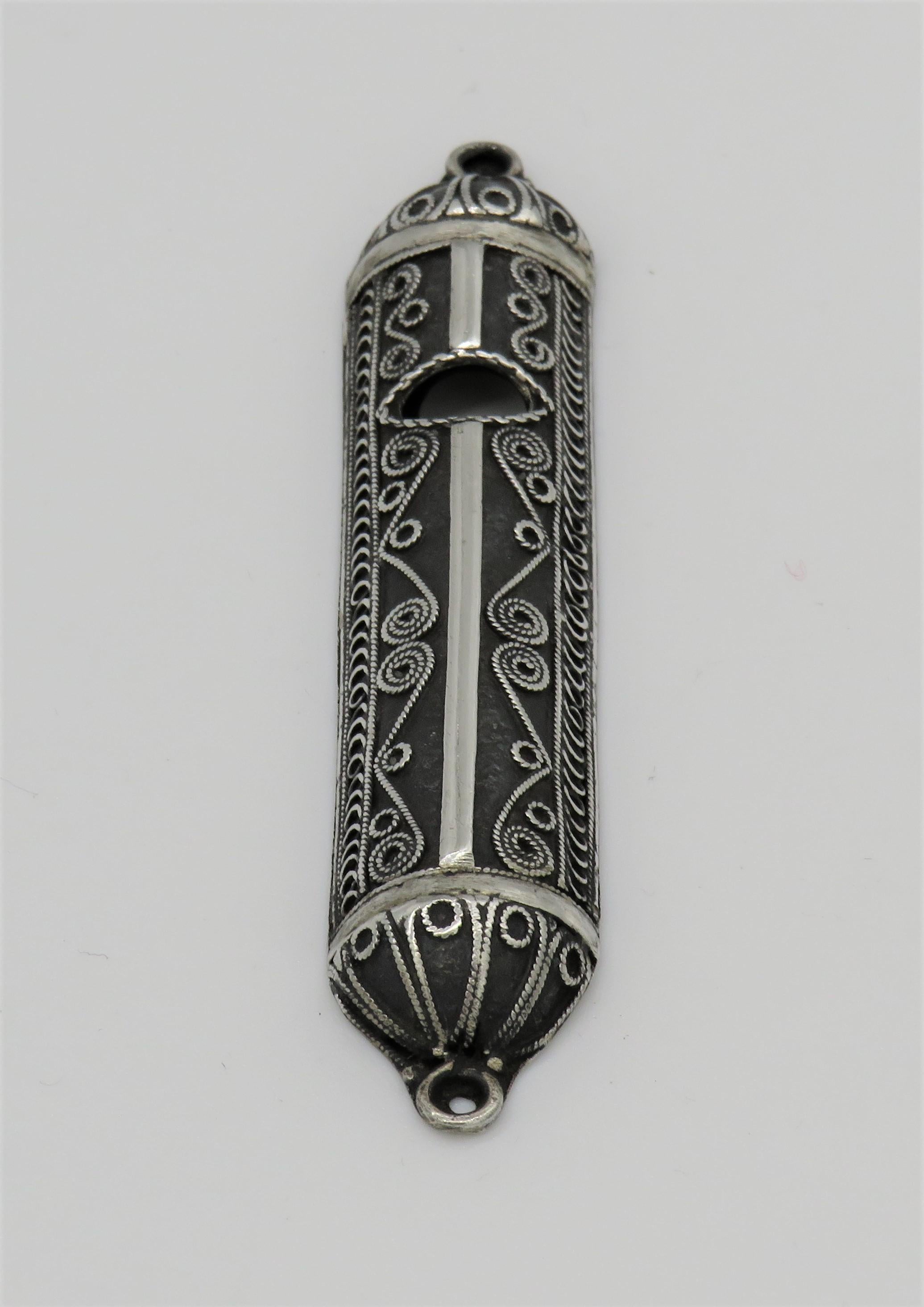 The Mezuzah is a tiny receptacle that houses a parchment scroll which contains two verses from the scriptures. It is attached to the doorway of every Jewish home.
This particular Mezuzah features fine silver filigree work by Yehia Yemini.

Yehia
