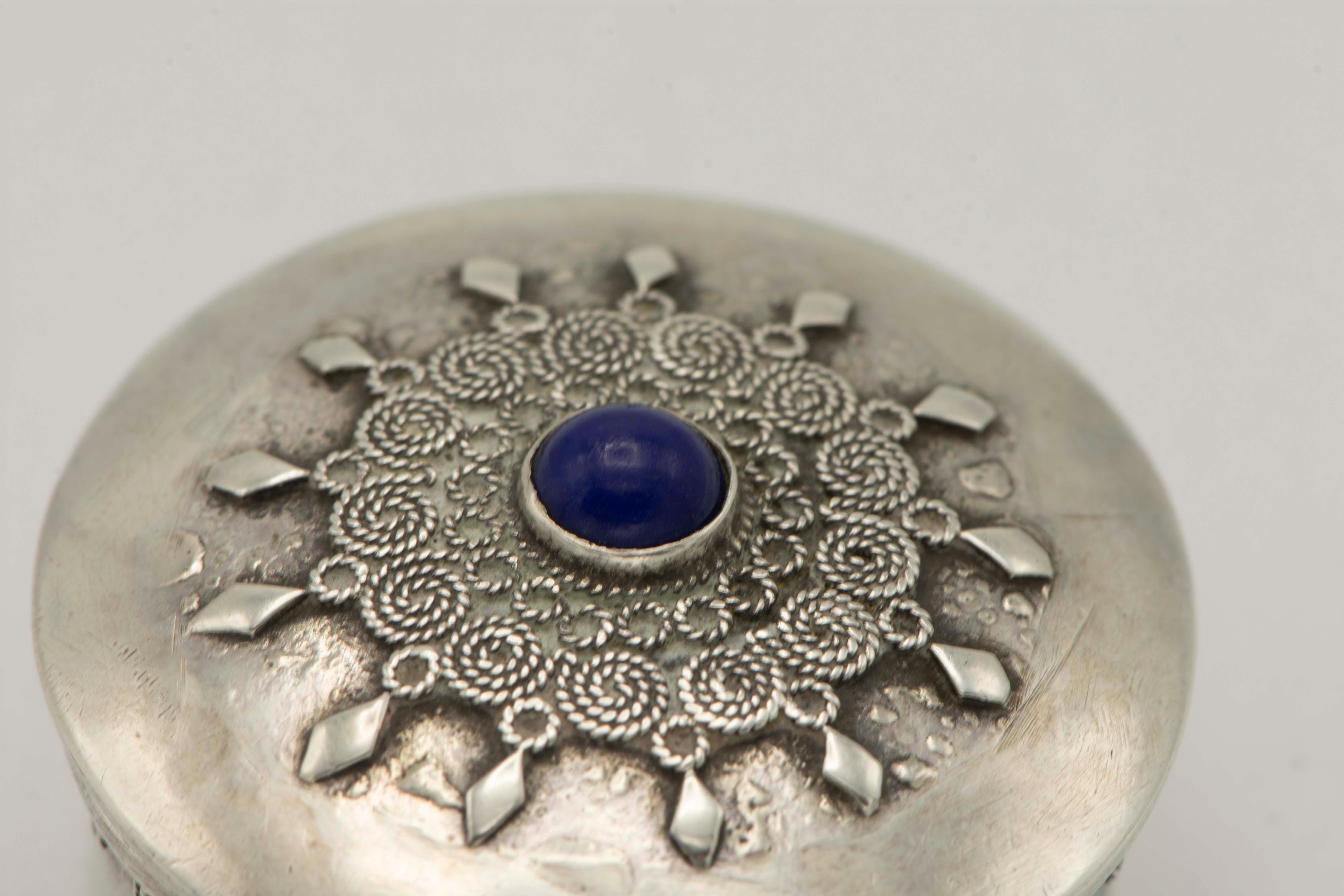 Handmade silver pill box by Bezalel school, Jerusalem, circa 1920.
Decorated with blue stone and silver filigree on the cover and around the rim.
Stamped on the bottom 