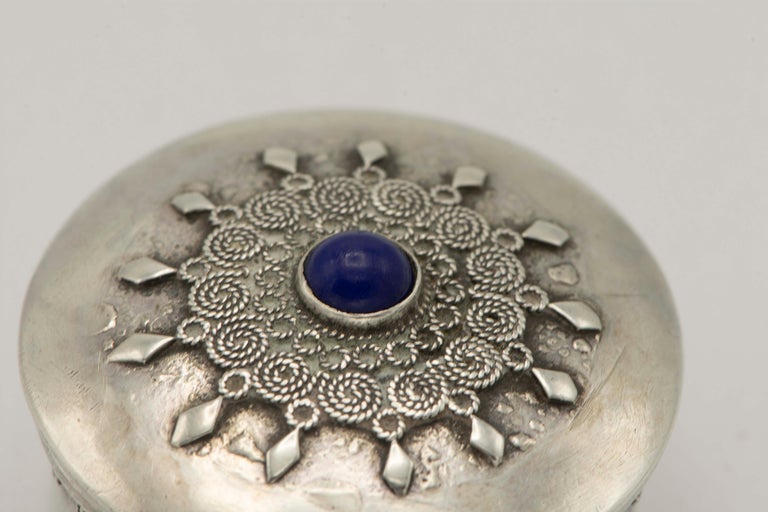 Handmade silver pill box by Bezalel school, Jerusalem, circa 1920.
Decorated with blue stone and silver filigree on the cover and around the rim.
Stamped on the bottom 