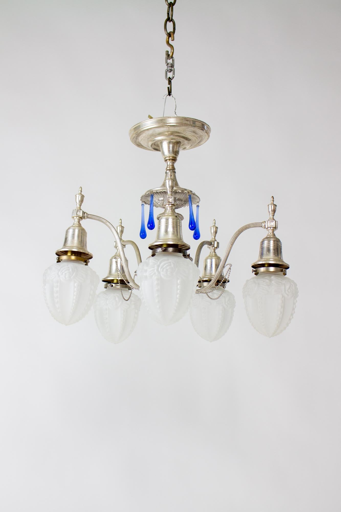 Early 20th century silver plate flush chandelier with blue crystals and frosted glass shades. Elegant Silver plate fixture, flush mount, with decorative stem and five arms that curve out and up to hold five down facing lights. Blue teardrop crystals