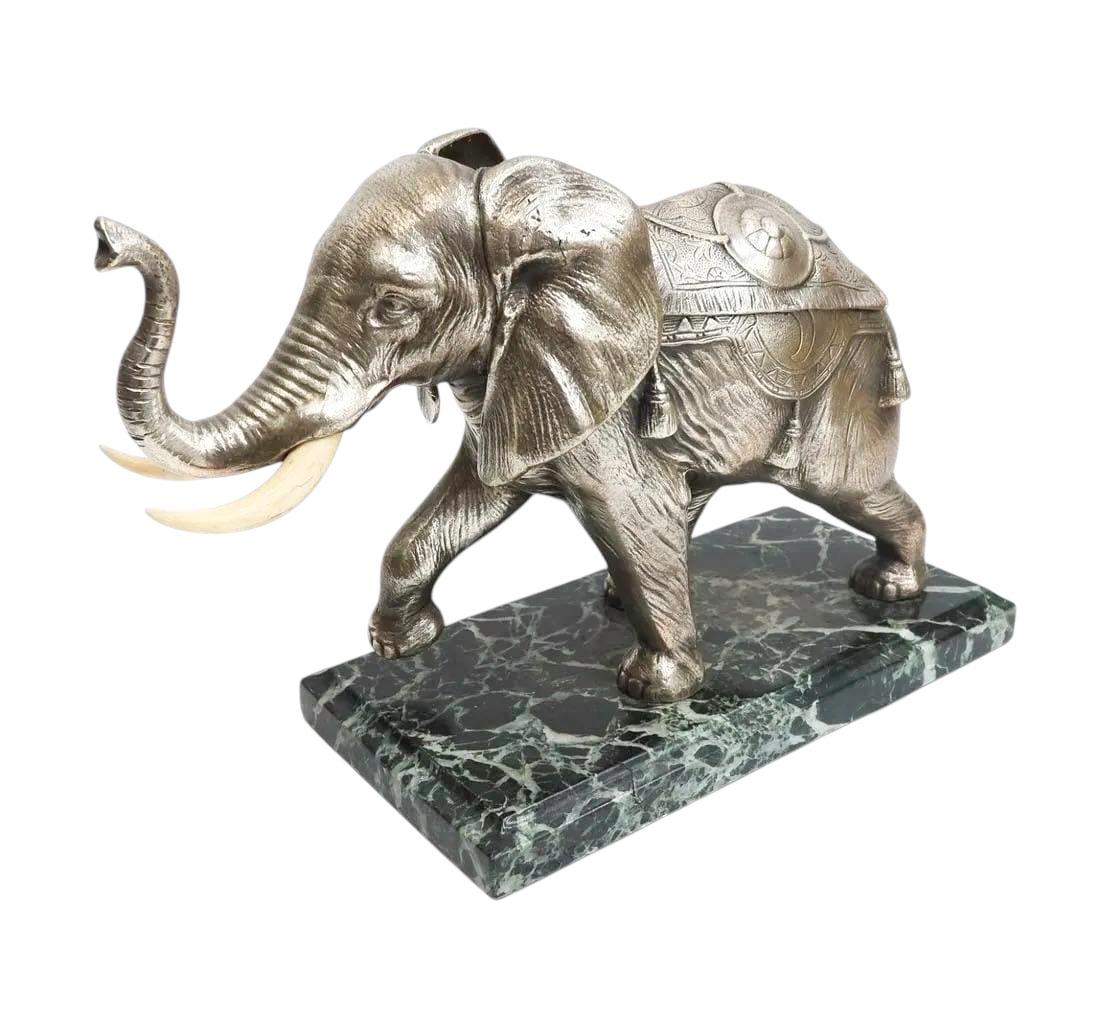 Tintero de bronce plateado de principios del siglo XX con forma de elefante en celo en plena cabalgada con la trompa levantada, la manta abriéndose para revelar tinteros dobles. Sobre una base de mármol verde veteado blanco con el borde moldeado.