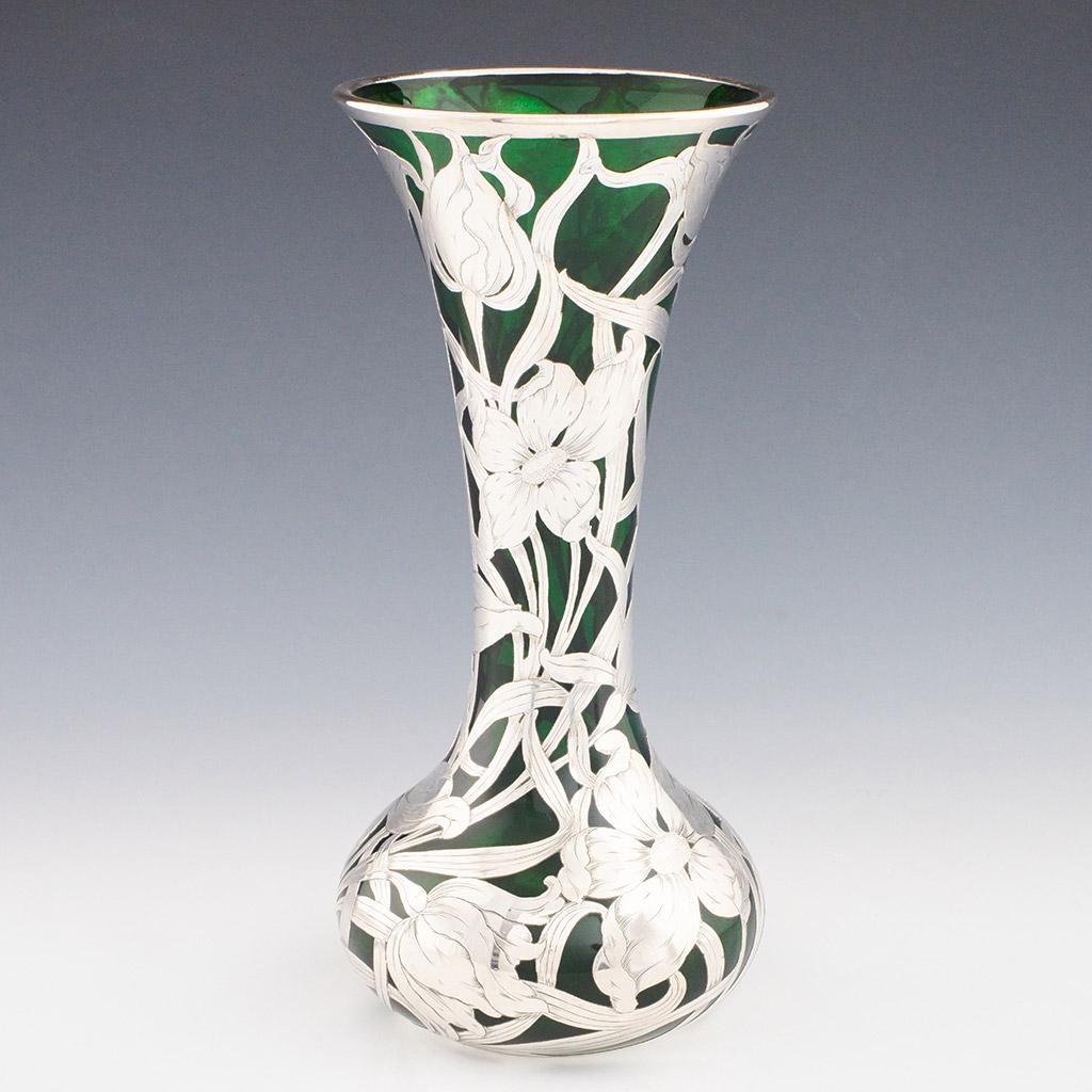 Visually striking early 20th Century American green glass vase of bulb form with everted undulating rim applied with deep silver Art Nouveau decorative design representing flowers and border motifs. Stamped 'Silver' to base rim

ADDITIONAL