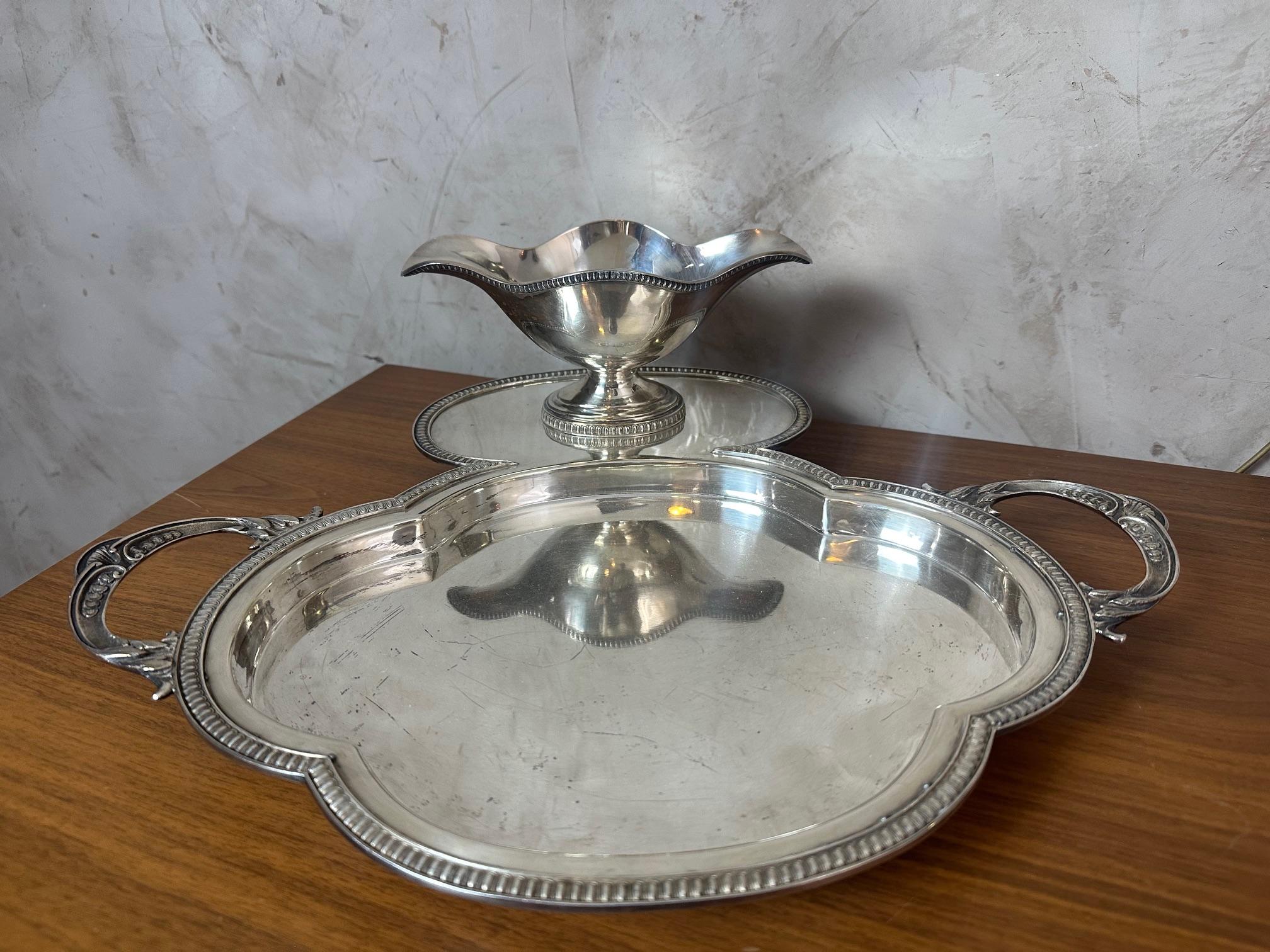 Elegante servizio in argento composto da un piatto da portata con manico e dalla salsiera abbinata, risalente agli inizi del XX secolo.

Il piatto è caratterizzato da una forma smerlata, impreziosita da un bordo a forma di gadroon e da manici