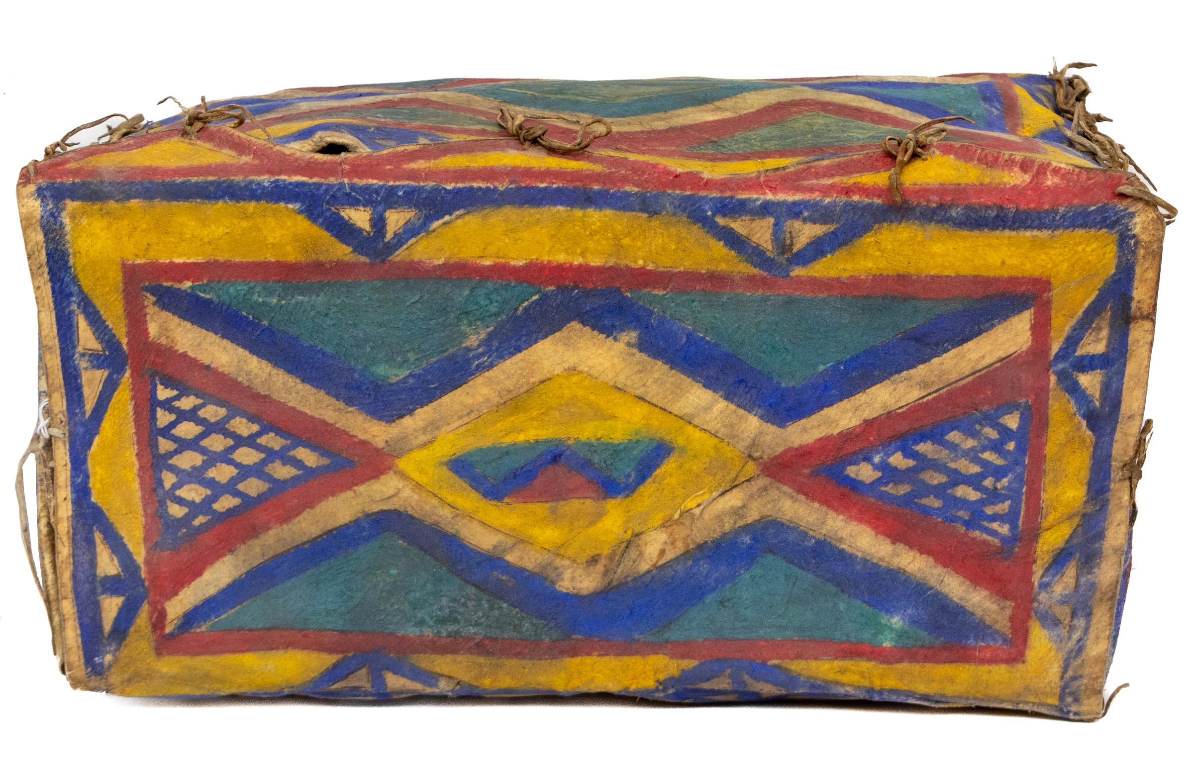 This early 20th-century Sioux parfleche box, crafted circa 1900, is a striking example of Native American artistry and design. Made from stretched and stiffened hide, the box is hand-painted with bold, symmetrical geometric patterns in richly