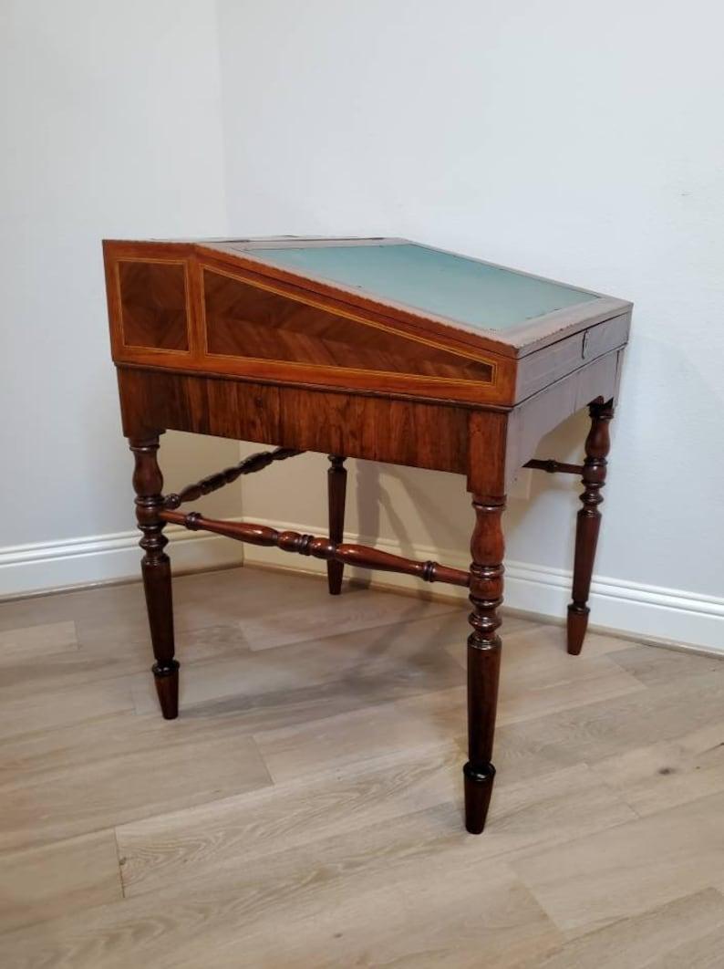 A rare and exceptionally inlaid antique slant-front drafting desk. circa 1900

Hand-crafted in the early 20th century, likely French, one piece desk on frame form, having a sloped front with inset felt writing surface garnished with gilt brass