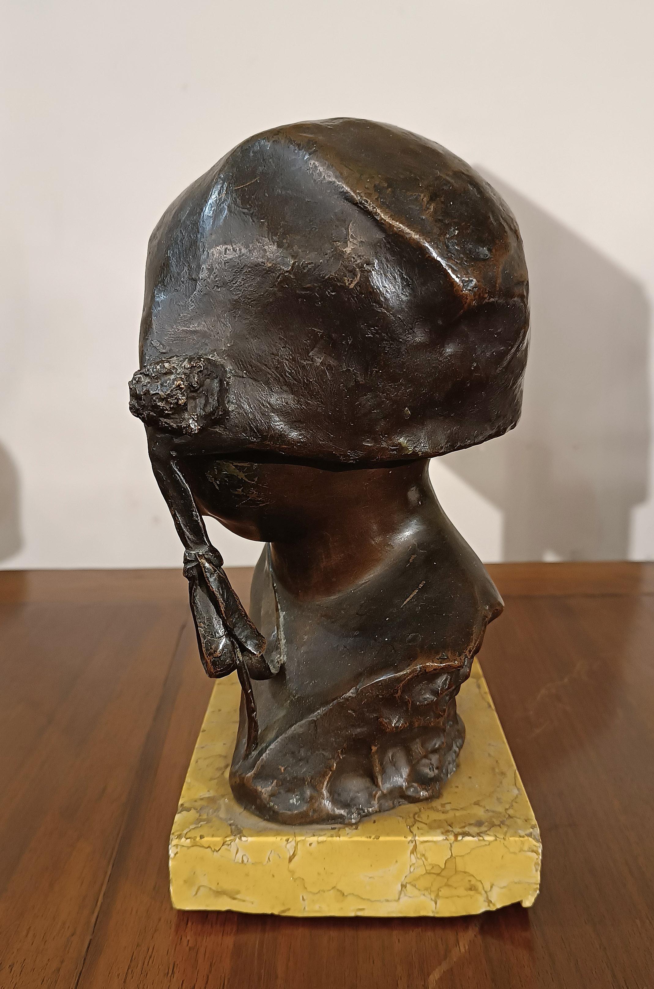 Elegant bronze bust, made using the lost wax technique and hand-chiseled. The sculpture is mounted on a parallelepiped base in yellow marble, which enhances its stability and support. The bronze represents the face of a smiling child, with a sweet