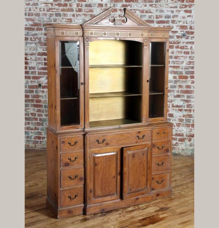 Early 20th century small Georgian style breakfront bookcase. Made of pine with two doors and central shelves over a secretaire desk drawer above cupboard. Flanked by eight smaller drawers. Crowned with a broken arch pediment and dental cornice.