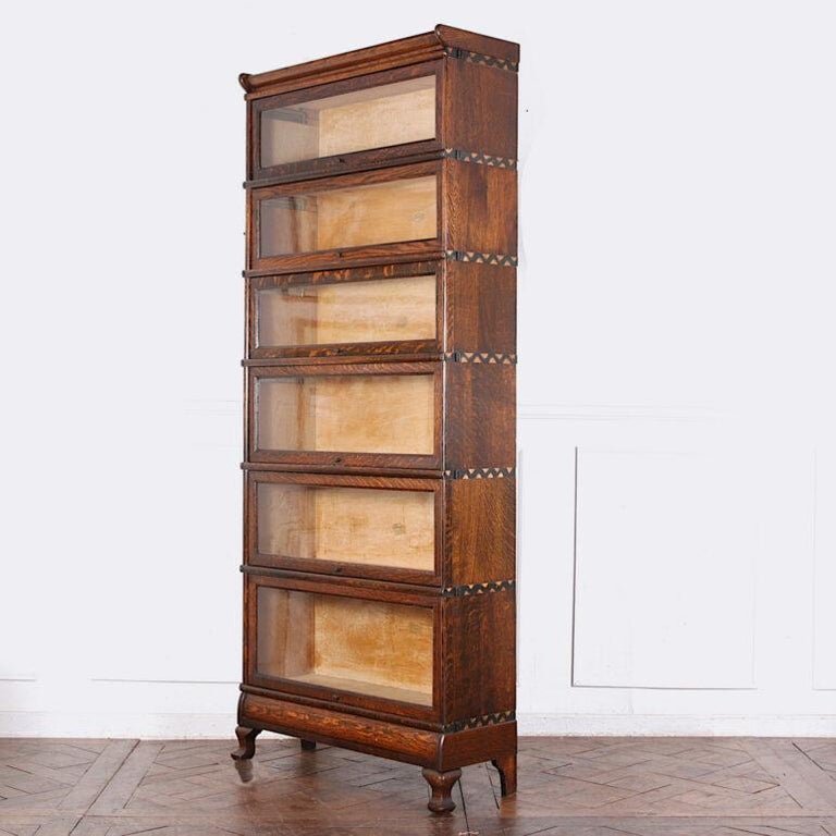 
Unusual solid quarter-sawn oak lawyers’ or barristers’ bookcase consisting of six graduated sections with contrasting copper trim, and the original base and crown. This modular piece comes apart for transport. Hinged retracting glass doors as