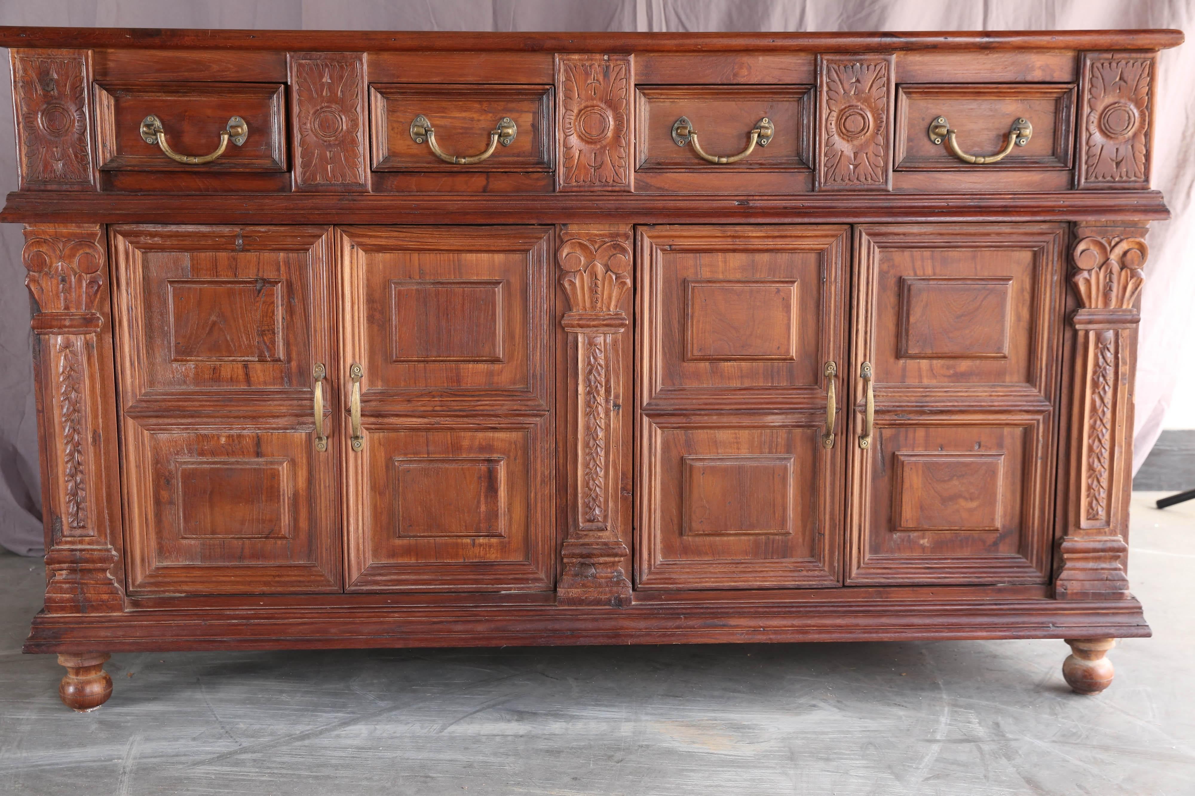 An unique custom-made solid teak wood credenza from a French Colonial home in Asia. It has four upper drawers and two large bottom shelves. It is mounted on ball feet. It retains original hand cast brass hardware. It comes from a town Pondicherry in