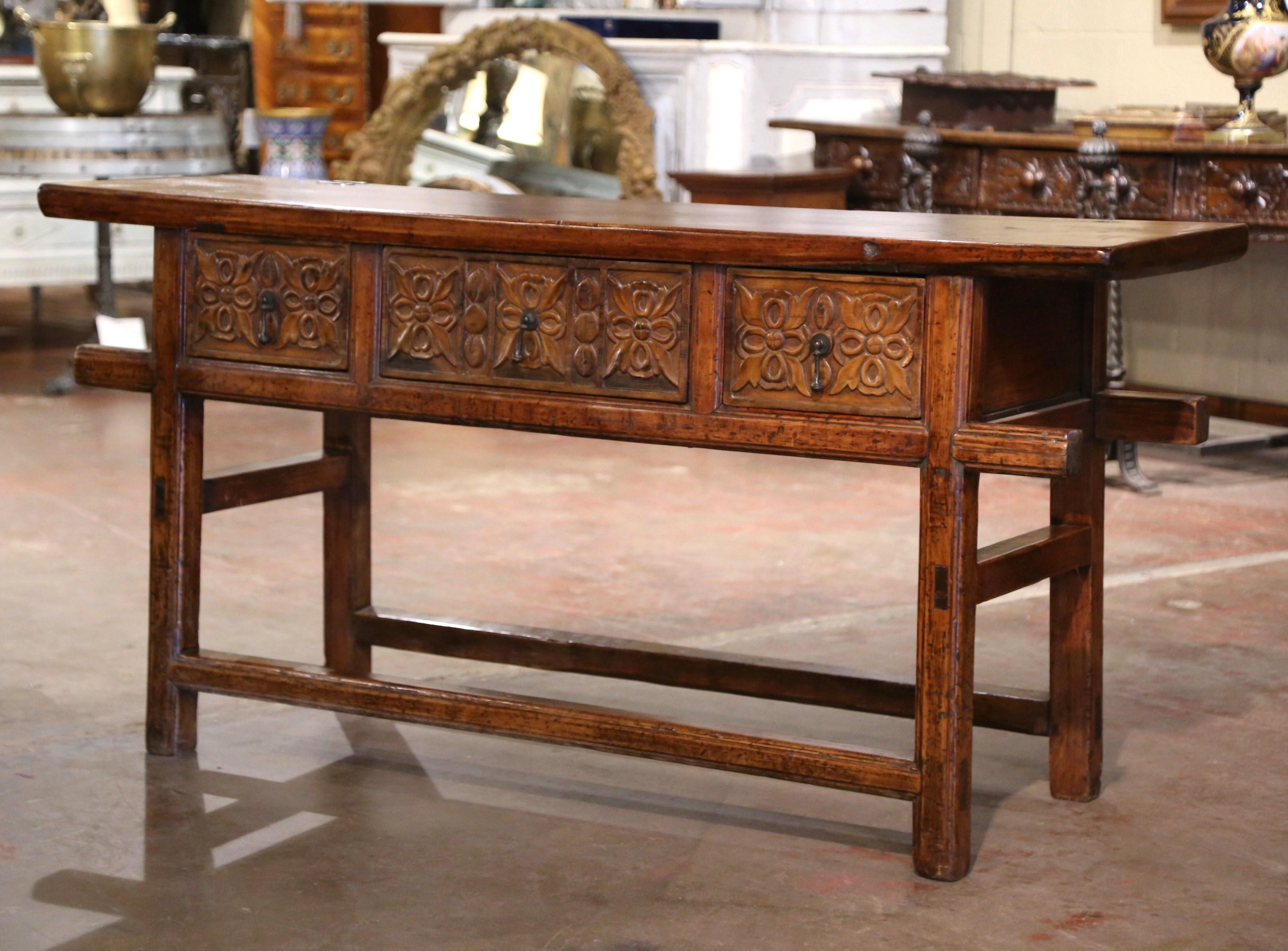 Place this elegant antique console table behind a sofa or against a wall. Crafted in Spain circa 1920 and built of oak and pine, the Baroque sofa table sits on square legs connected with a double bottom stretchers; the table features three hand