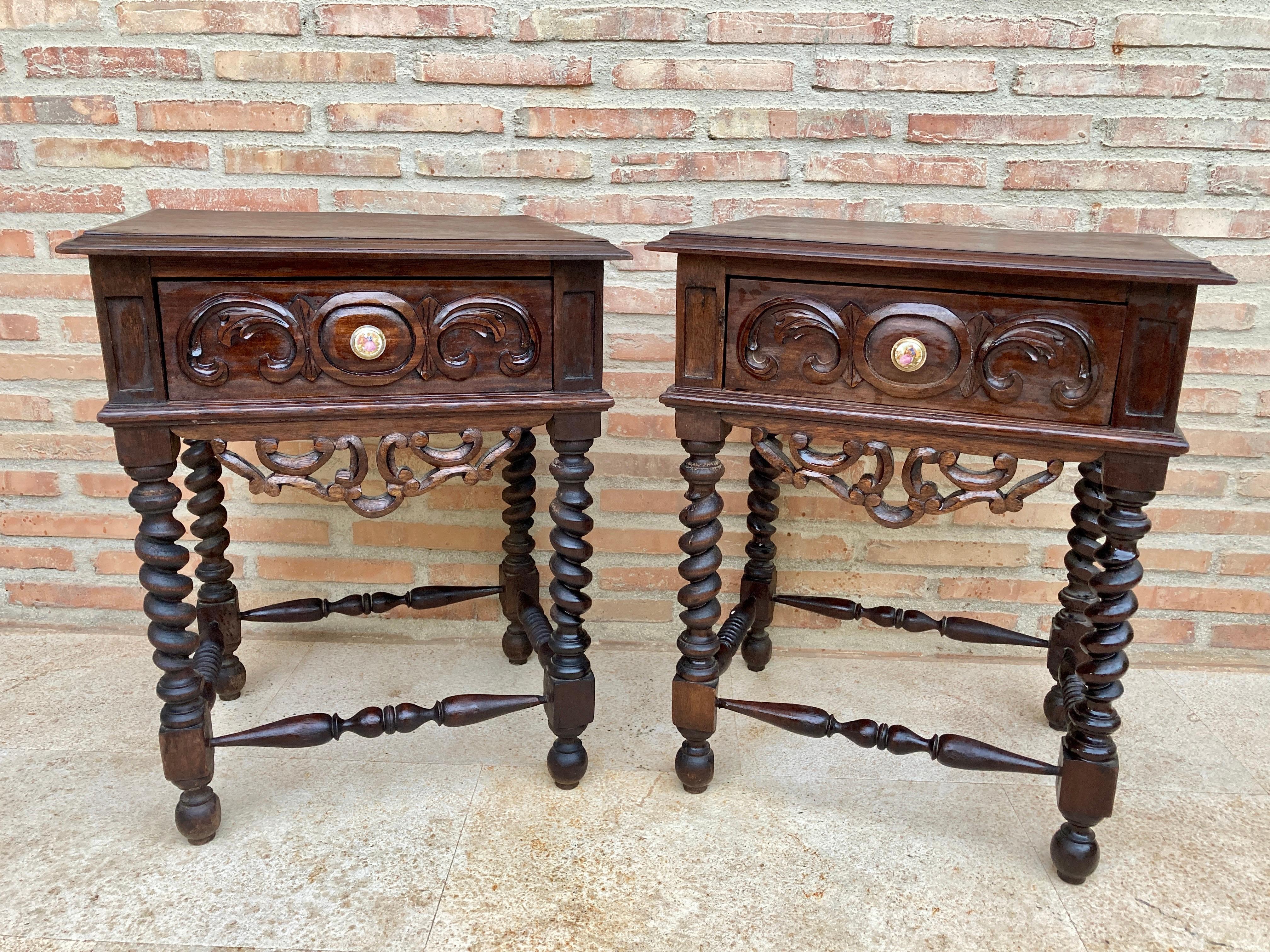 Pair of early 20th century Spanish baroque style walnut nightstands or bedside tables with one drawer and porcelain hardware. Beautiful nightstands in the Baroque style with turn legs.