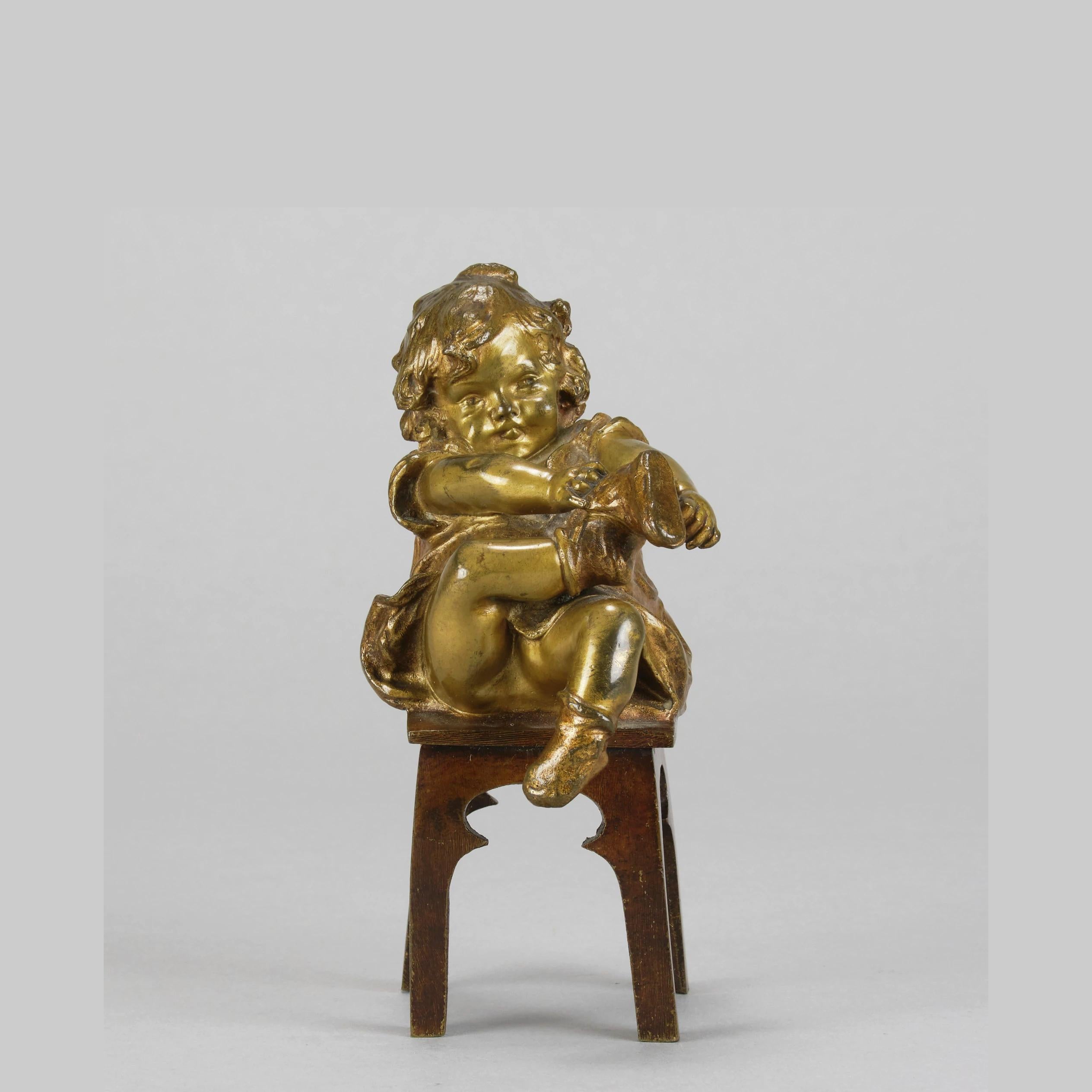 

An endearing early 20th Century Spanish patinated gilt bronze study of a young girl sitting upon a stool  whilst putting on her shoe. The surface of the bronze with excellent rich brown and gilt patina and fine hand finished surface detail. Signed