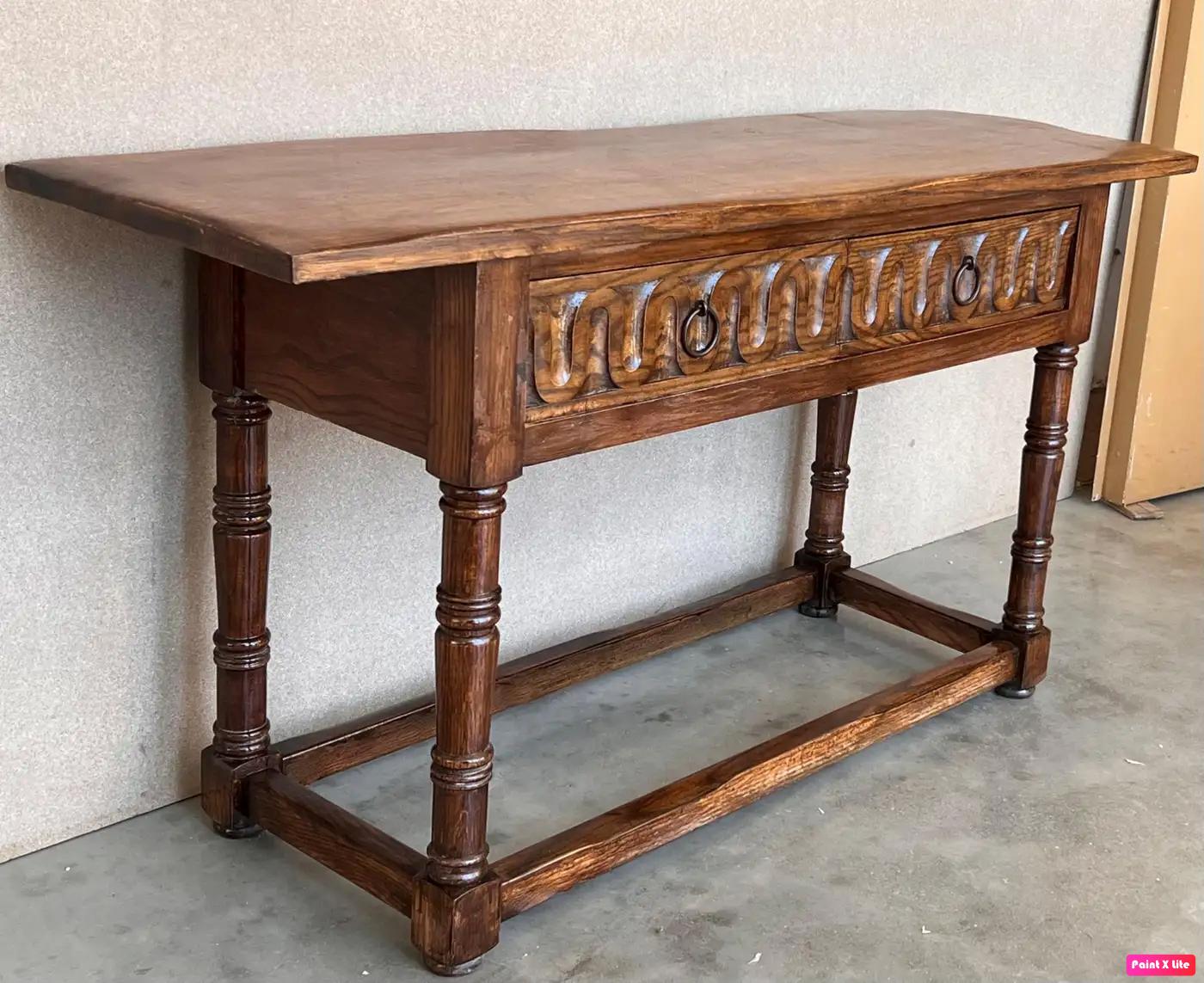 Early 20th century carved Spanish console with two drawers.
This table with character is of rare narrow depth. It is characteristic of Spanish Baroque furniture with a thick one-piece top, a simple and bold chip-carved ornate drawers, and bold