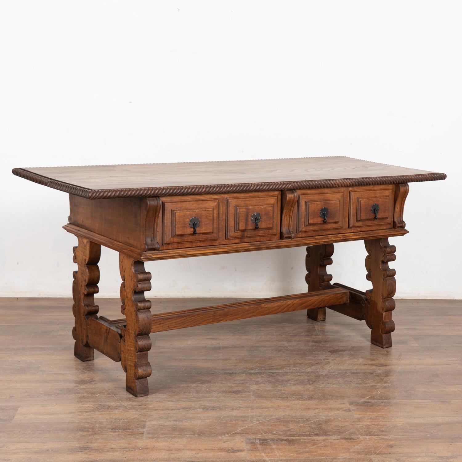 It is the rich, aged patina of the wood that draws one to this handsome Spanish carved oak console table with two functioning drawers.
The heavily carved legs with stretcher are dramatic, while the top reflects generations of use as seen in the dark