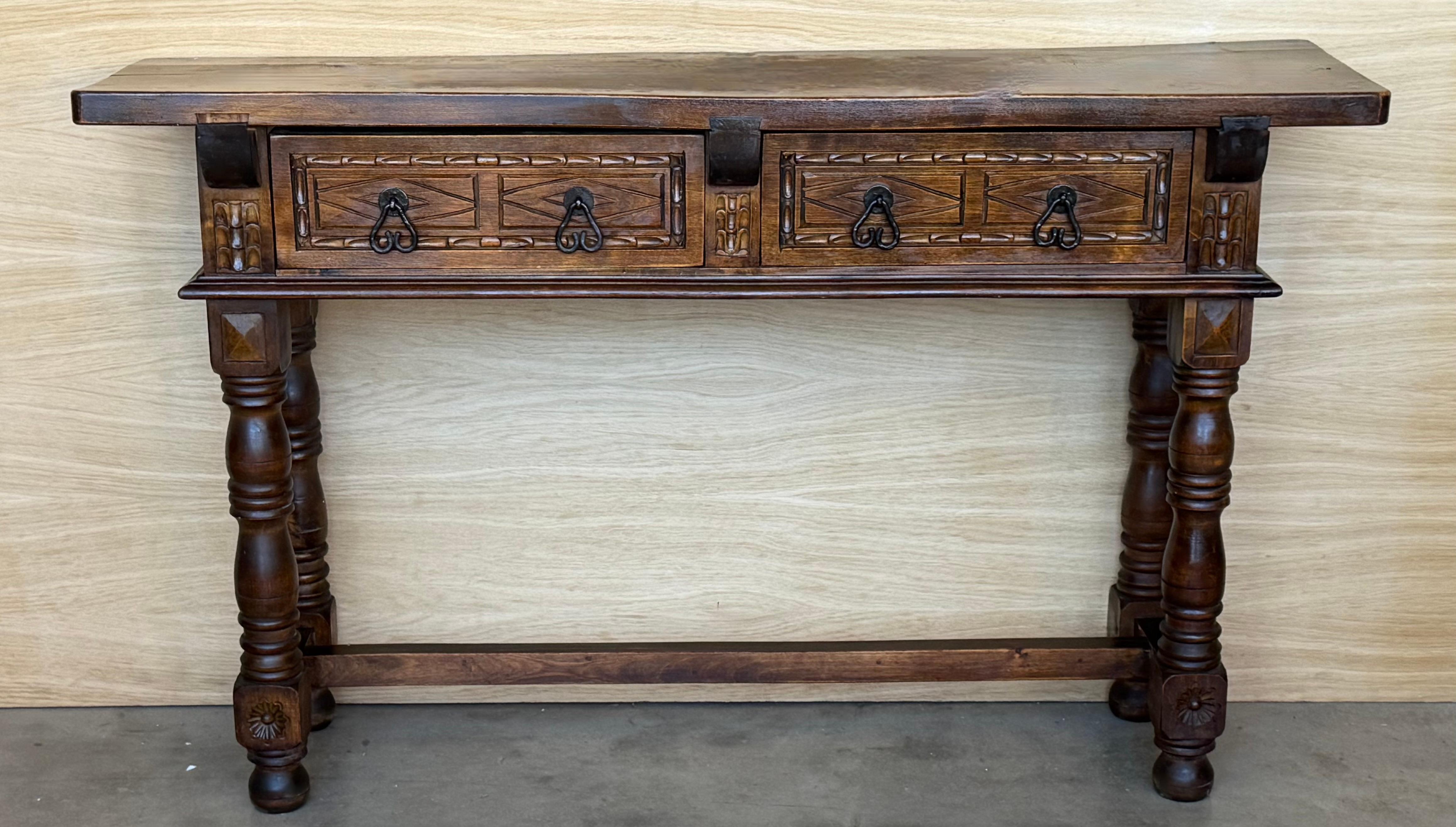 
Spanish Baroque furniture with a single piece top. It has a rich lustrous patina. The thick single plank walnut top with fine figuring. The front fitted with two short drawers decorated with chip carving and with iron knobs. Standing on bold ring