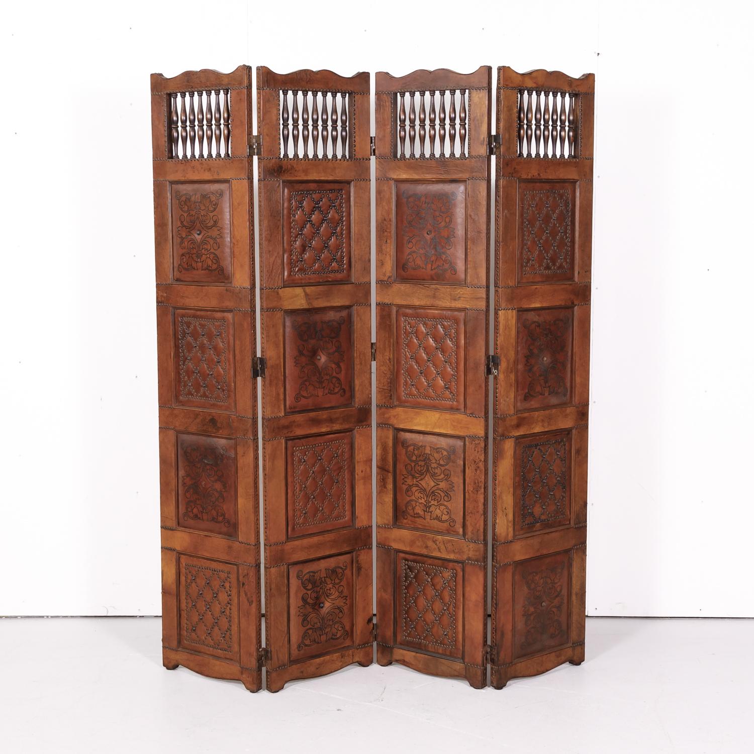 An early 20th century Spanish four-panel embossed leather screen handcrafted in Barcelona, circa 1900. This wonderful screen features four leather wrapped panels with walnut spindles each having four hand embossed leather panels with nailhead trim