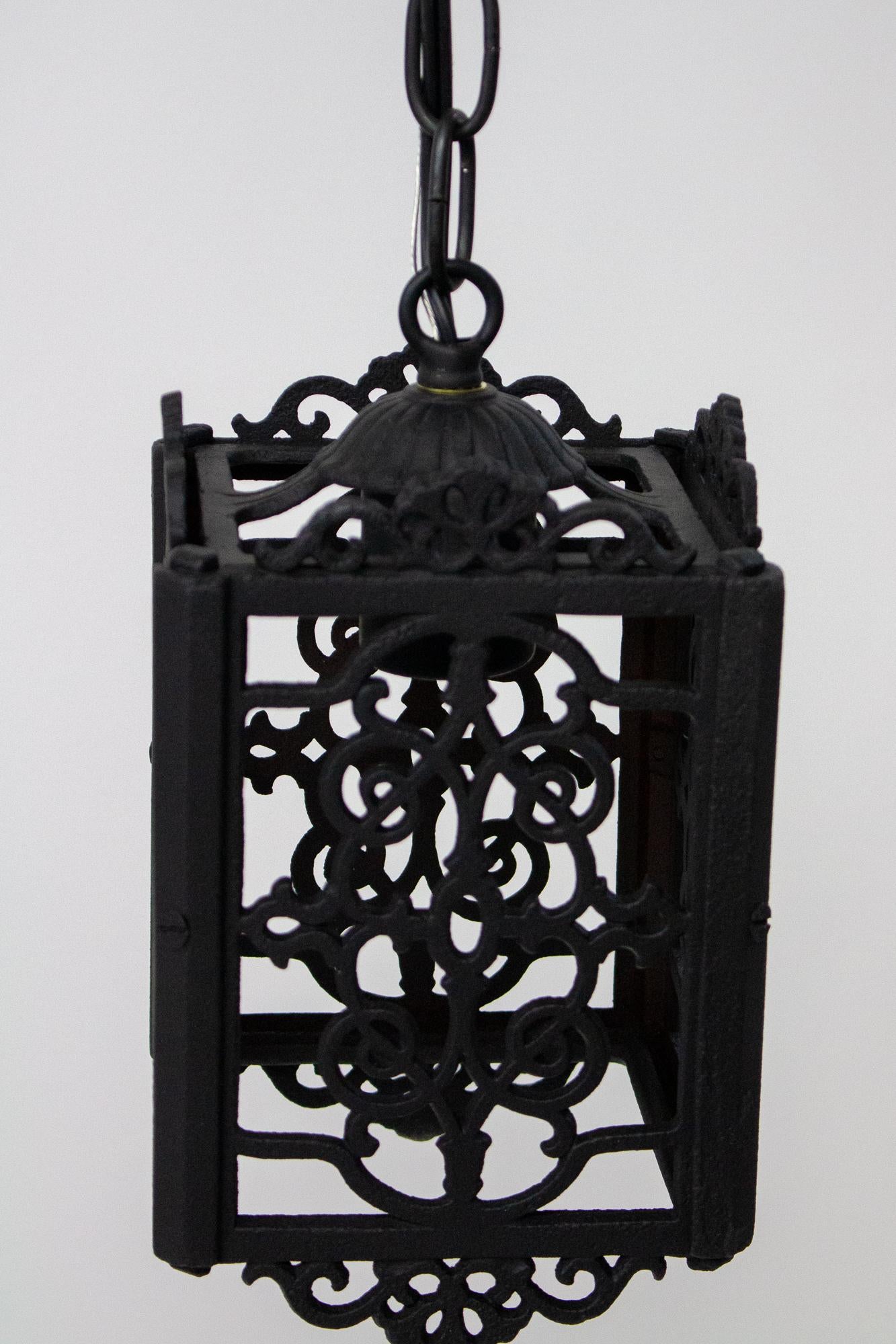 Square cast iron lantern. The panels have a cutout pattern and ornate top and bottom edges. The corners are beveled. Has been cleaned and repainted black. No glass, for interior use only. Rewired for use in the United States, a single porcelain