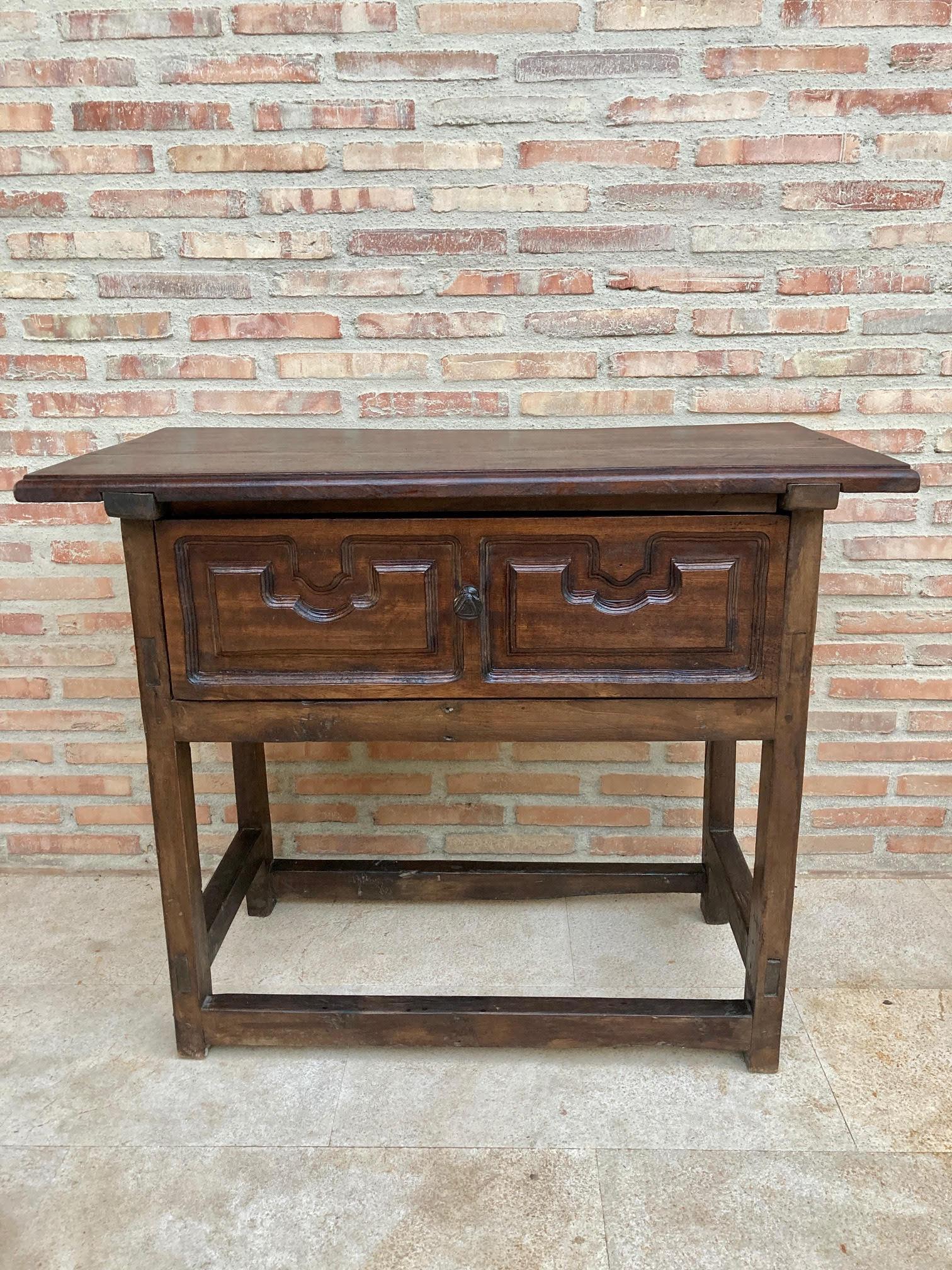 Early 20th century Spanish walnut work side table with large single drawer. 
A Spanish walnut side table with a wide drawer, carved front, and straight legs attached to straight counter beams from the early 20th century. 
This elegant Spanish