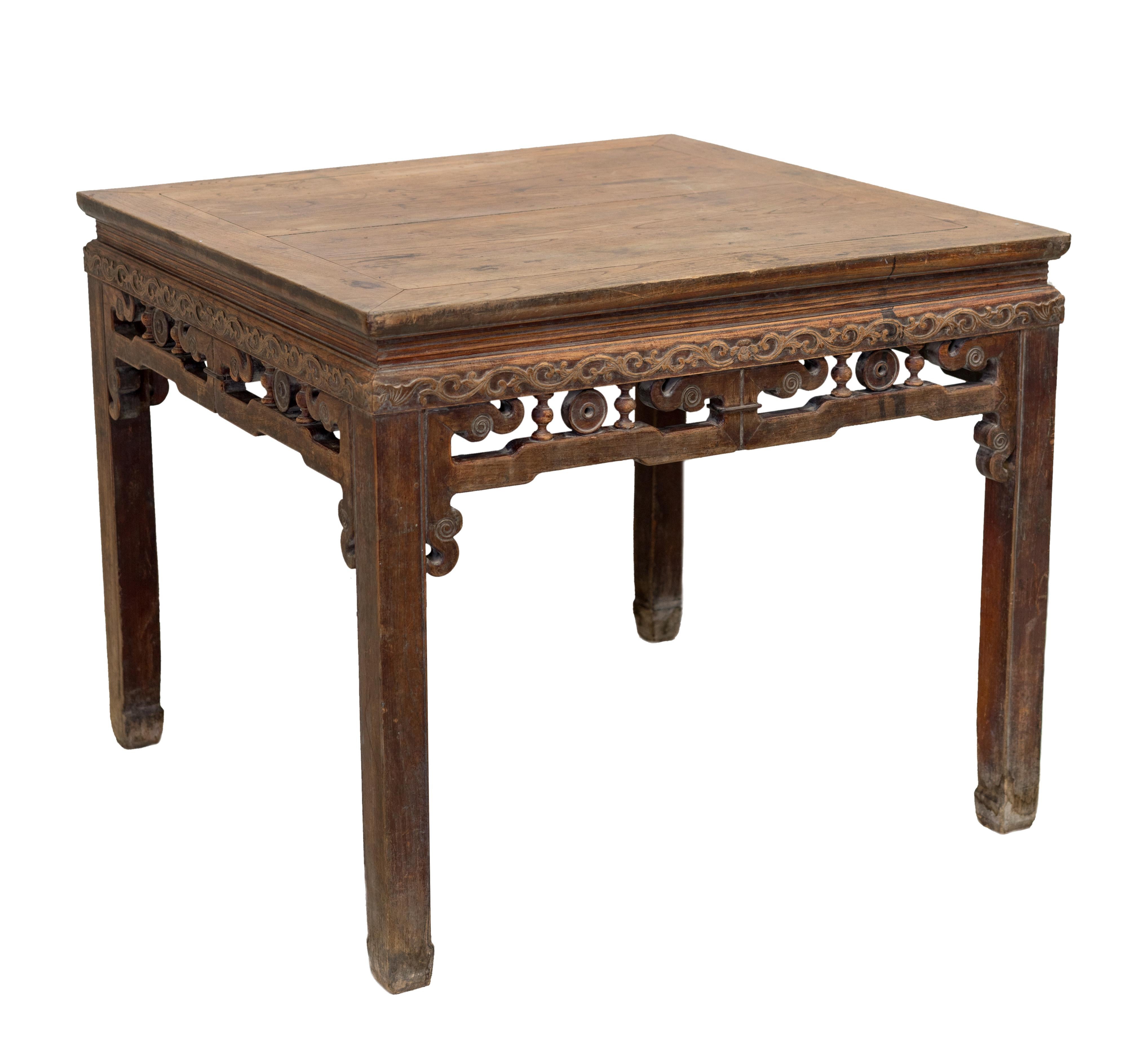 An early 20th century Jumu square waisted table from Zhejiang province, China. The tabletop consists of two panels joined in the middle. It has carvings of floral and vine motifs around the four sides and carvings of a bat at every corner. The