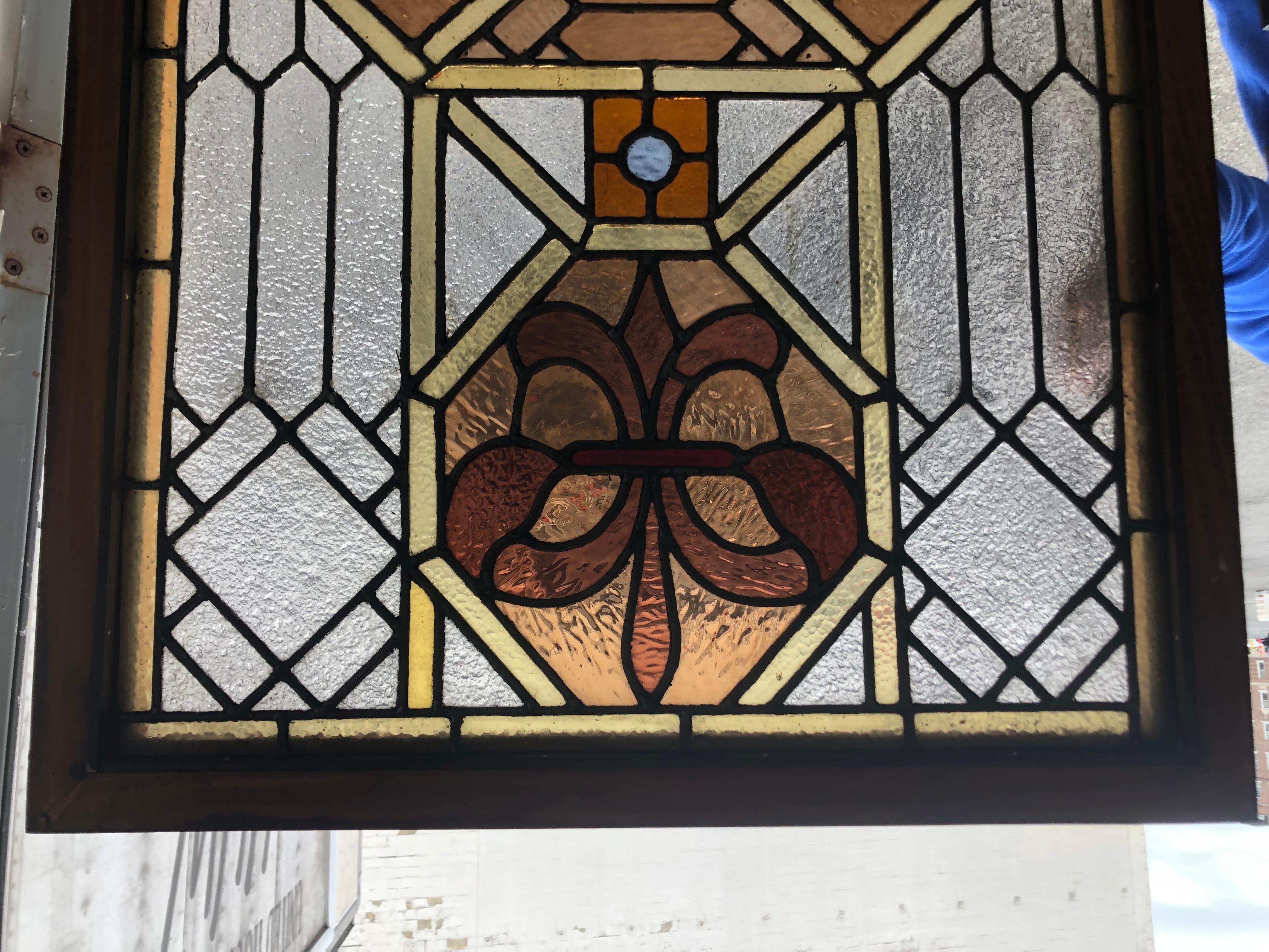 Beautiful Antique Early 20th Century leaded stained glass window with a Jeweled center and Fleur De Lis pattern on the top and bottom. It is in great condition and would look fantastic in front of any window or behind a home bar.
