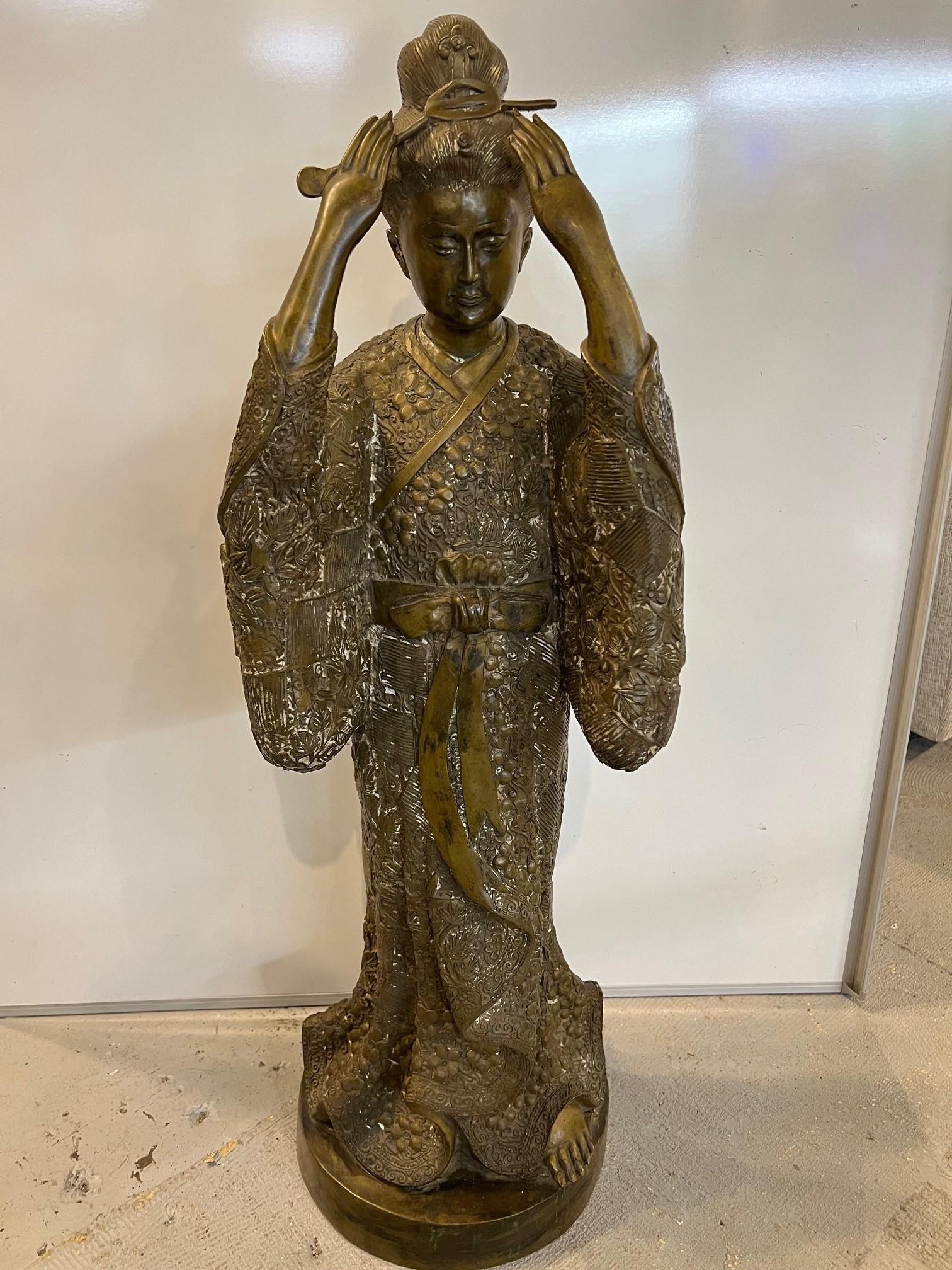 Beautiful bronze figure of a standing Japanese geisha in a traditional kimono with an obi. The geisha's susohiki kimono is laced with an intricate pattern of flowers, leaves and vines. Geisha are a class of female Japanese performing artist and