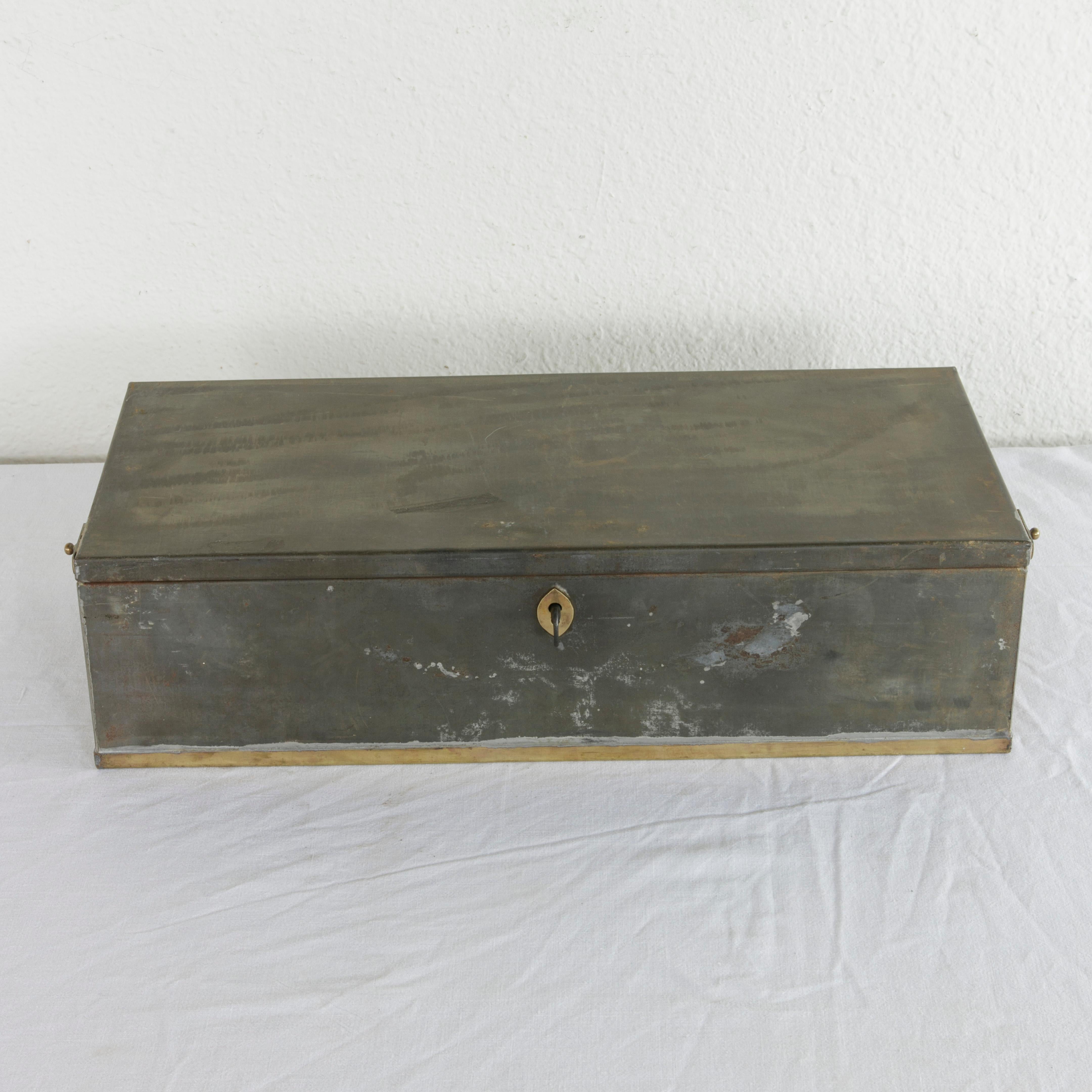 This early 20th century steel lock box or safety deposit box from the Banco Central of Barcelona in Spain features its original brass handles, trim, and key entry. The hand-painted number 317 is on one side, and the box includes its two original