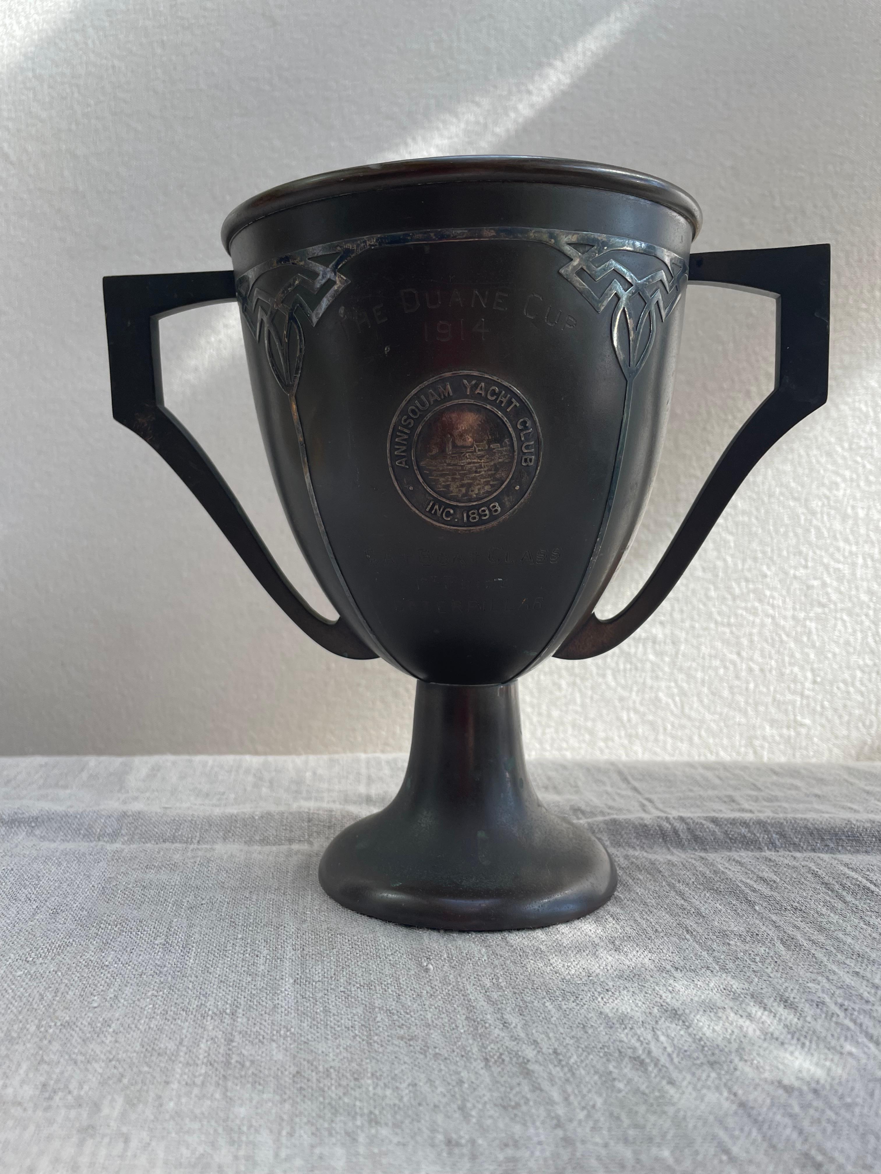 
Un remarquable trophée de présentation en sterling sur bronze, décerné en 1914 sous le nom de Duane Cup par l'historique Annisquam Yacht Club (fondé en 1898 à Gloucester, Massachusetts). Cette forme de coupe d'amour à deux anses présente des