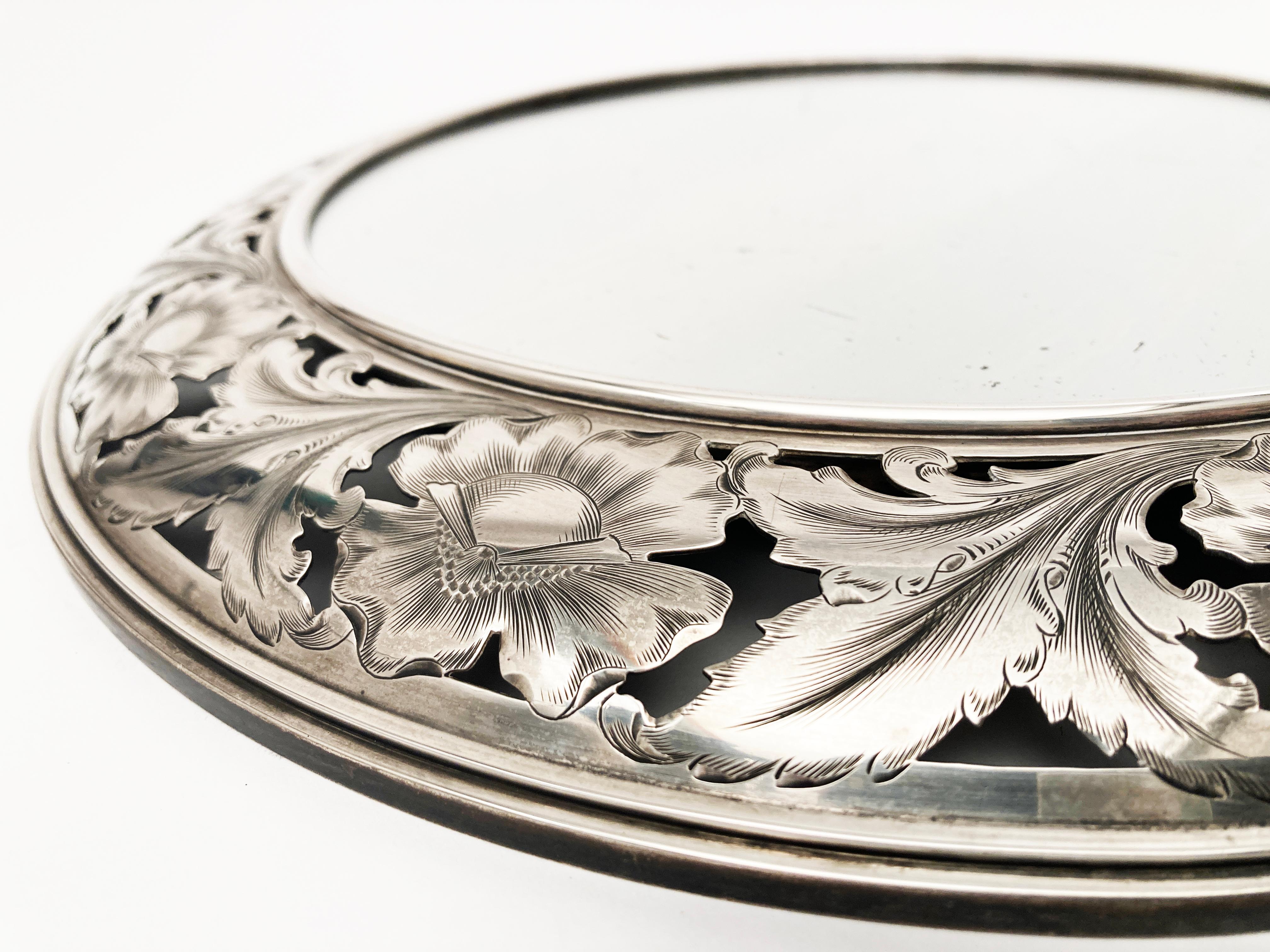 Dieser verschnörkelte, kreisförmige Spiegel mit Sterlingsilberrahmen hat detaillierte florale und blattartige Schnitzereien/Ätzungen im Silber mit Netzstruktur, die diesen Wandspiegel außergewöhnlich machen. Das Stück ist auf der Rückseite mit