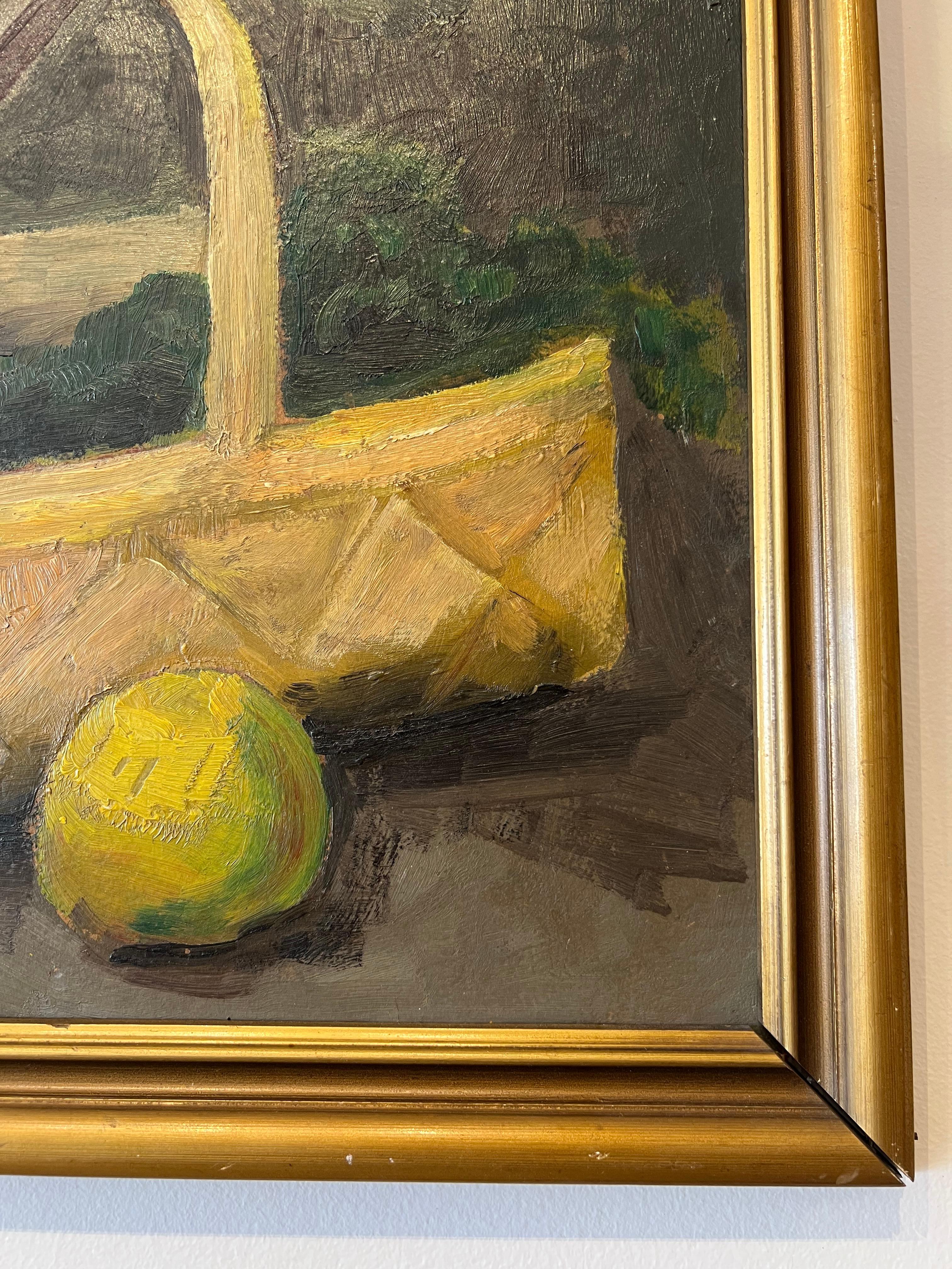 This early 20th-century still life oil painting on board by Carl Fischer captures a warm, impressionistic composition featuring a rustic woven basket of vegetables, bright citrus, and a ceramic pitcher, set against a moody, dark-toned background.