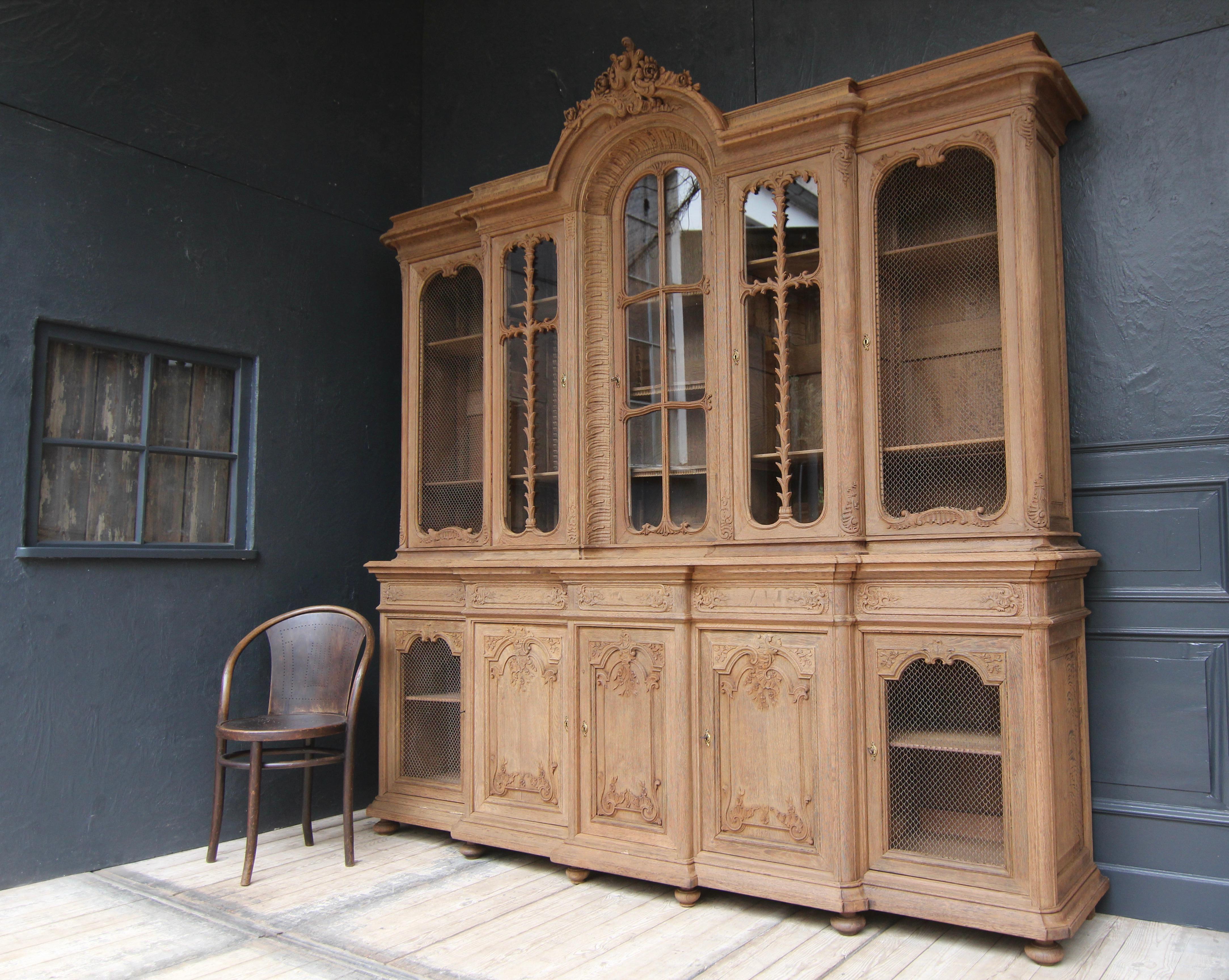 Large display cabinet or bookcase in the style of the Aachen-Liège Baroque. Early 20th century. Made of solid oak with fine carvings. 

Two-part oak corpus on pressed ball feet, coffered at the sides, with central risalit, rounded edges and fluted