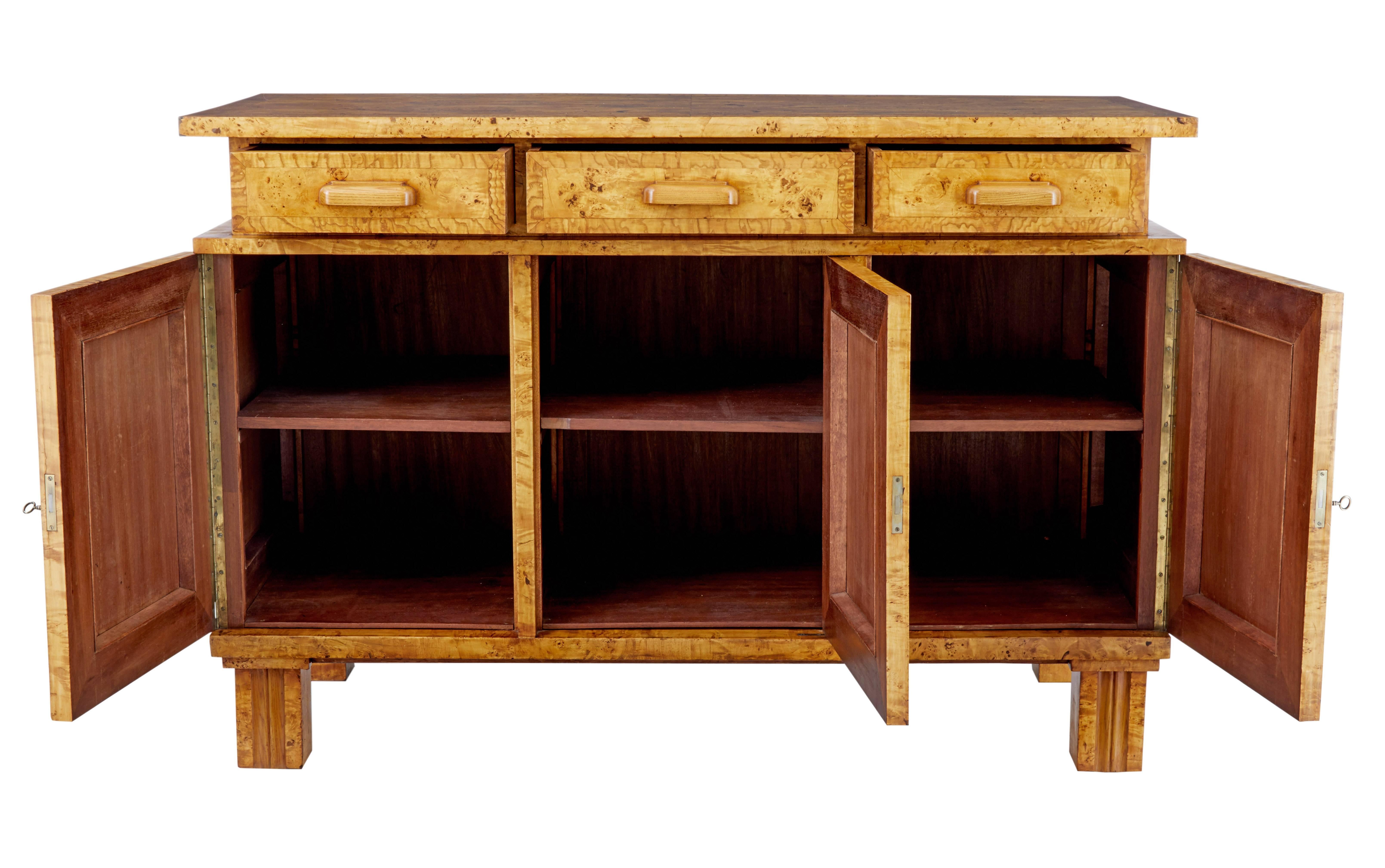 Stunning birch root sideboard of large proportions, circa 1910.

Over sailing cross banded top surface with three drawers directly below. Three single doors which open on the key to reveal a single drawer.

Standing on four straight fluted