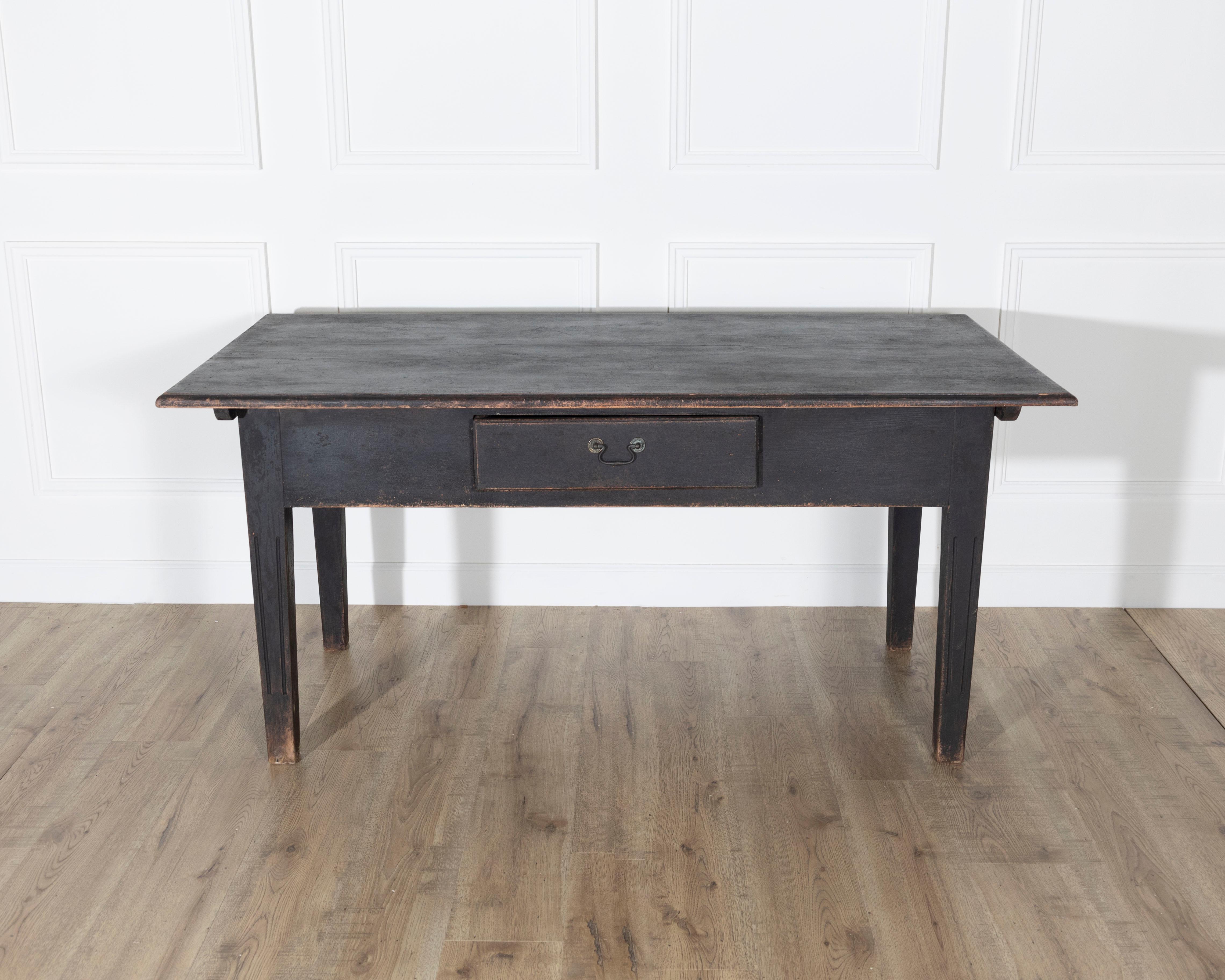 Une belle table de cuisine suédoise fabriquée en pin massif et recouverte d'une peinture noire mate usée qui met en valeur son charme rustique. Le généreux plan de travail rectangulaire mesure 162,5 cm sur 84 cm (environ 64
