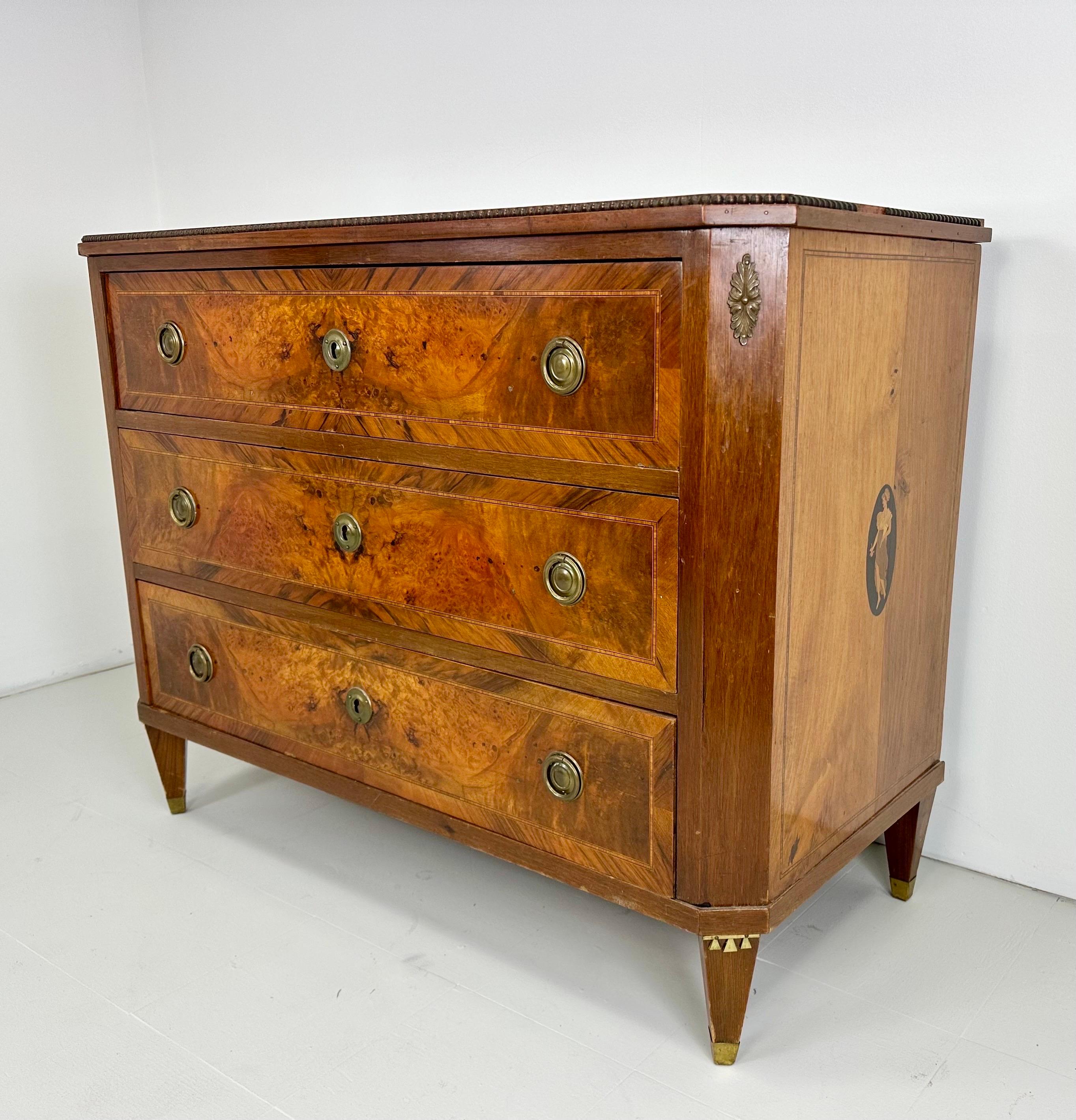 Cassettone svedese dei primi del Novecento. Affascinante comò a tre cassetti in mogano con intarsi e dettagli decorativi. Le gambe hanno dettagli in ottone. Motivi figurativi con venature del legno in tutta la struttura.