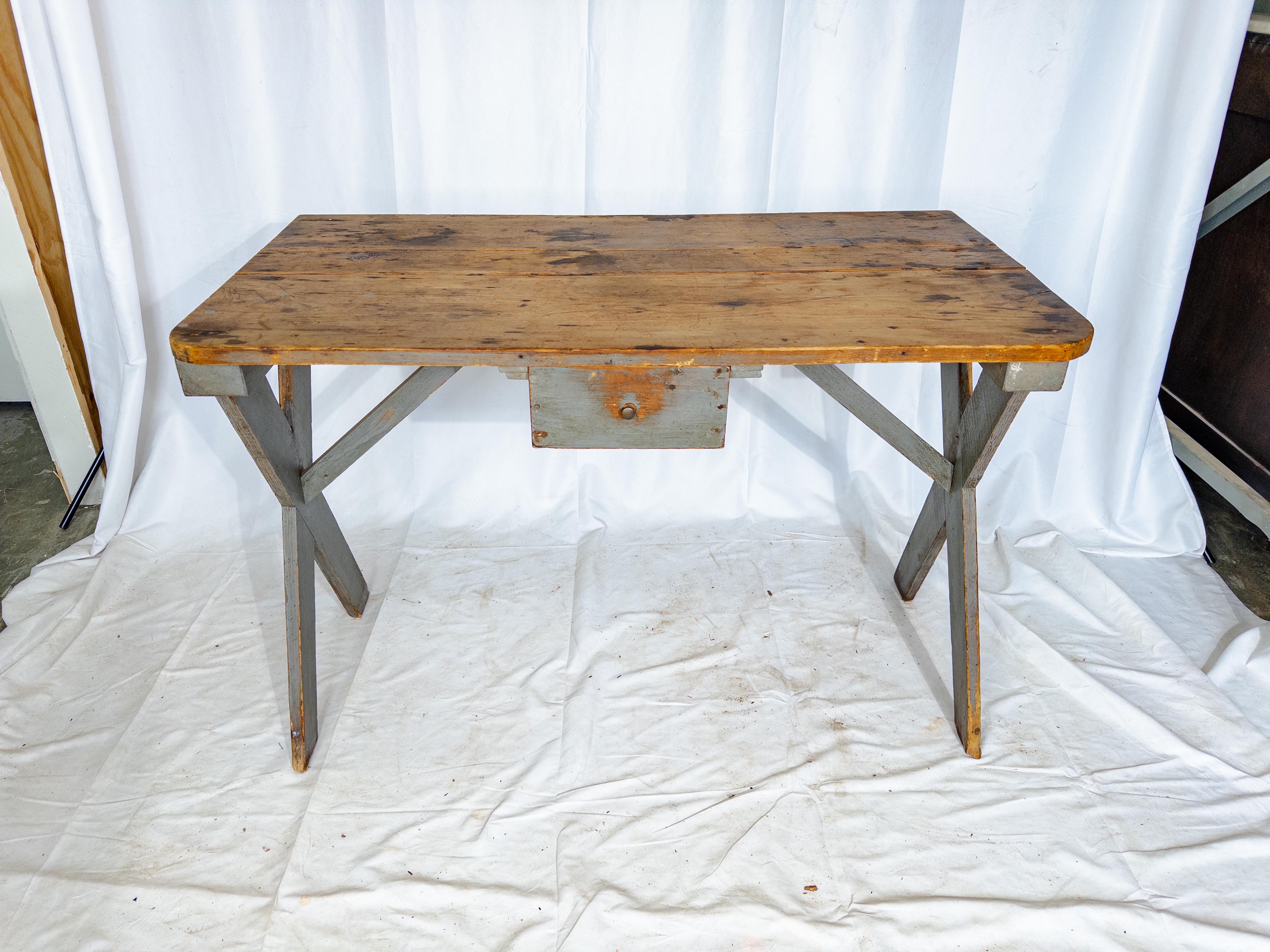 This early 20th-century Swedish farm table is a testament to simplicity and functionality, exuding rustic charm with its understated elegance. Crafted from sturdy wood, its table body wears a serene coat of blue-gray paint, reminiscent of the